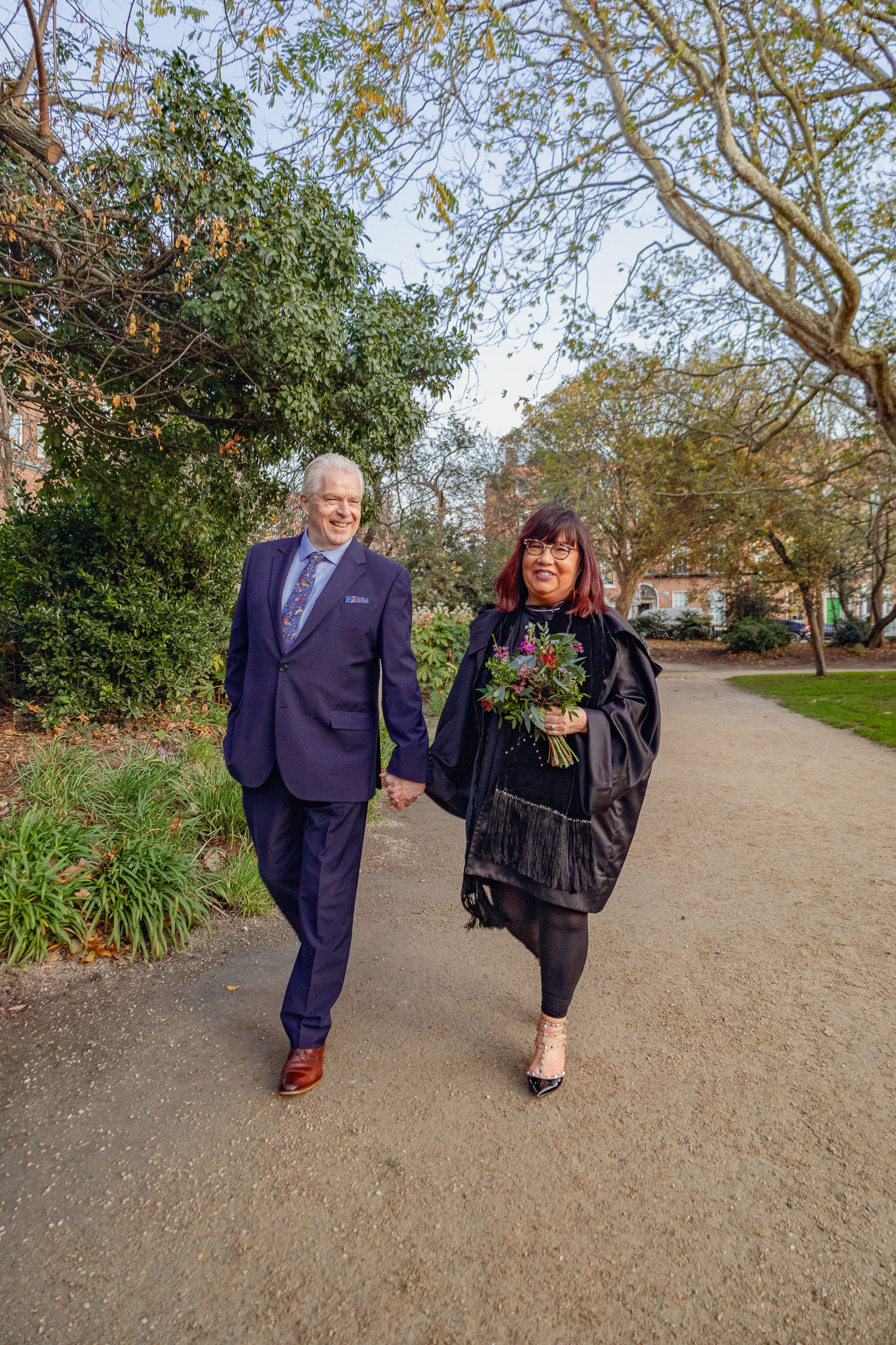 Wedding couple walk through park 