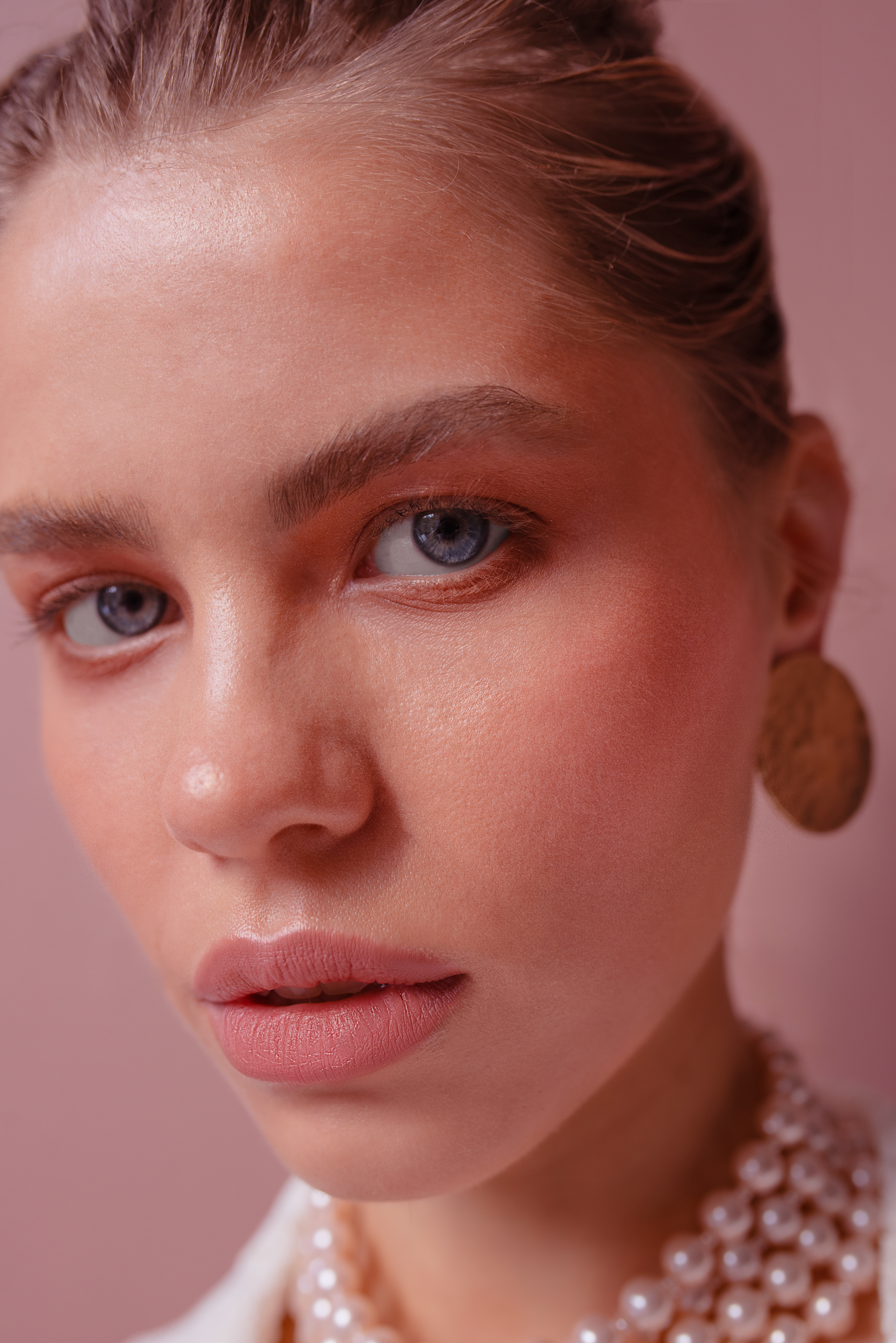 headshot of a woman with blue luminous eyes. Showcasing pearls and earrings.