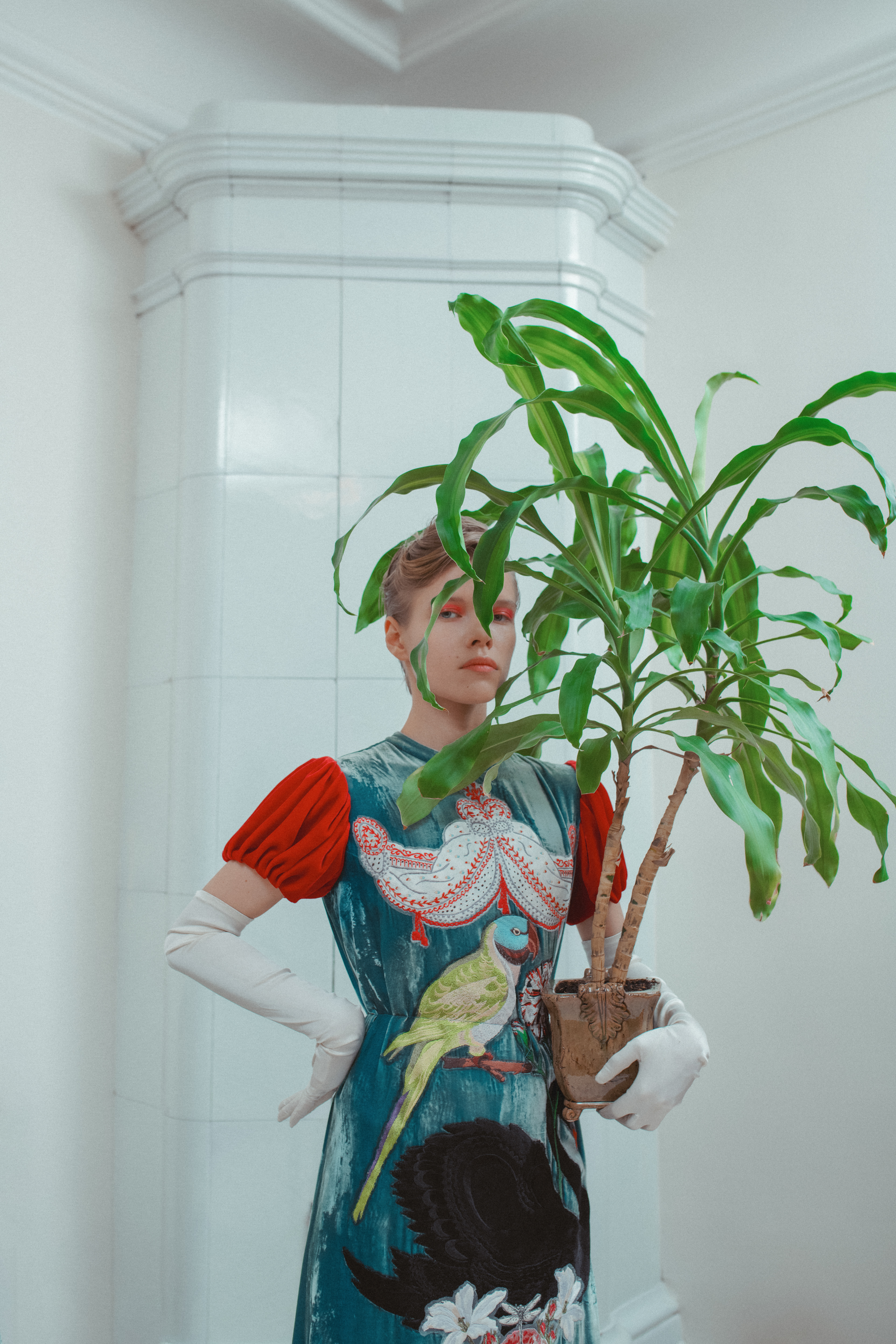 white tiled backrground with a woman holding a green plant.
