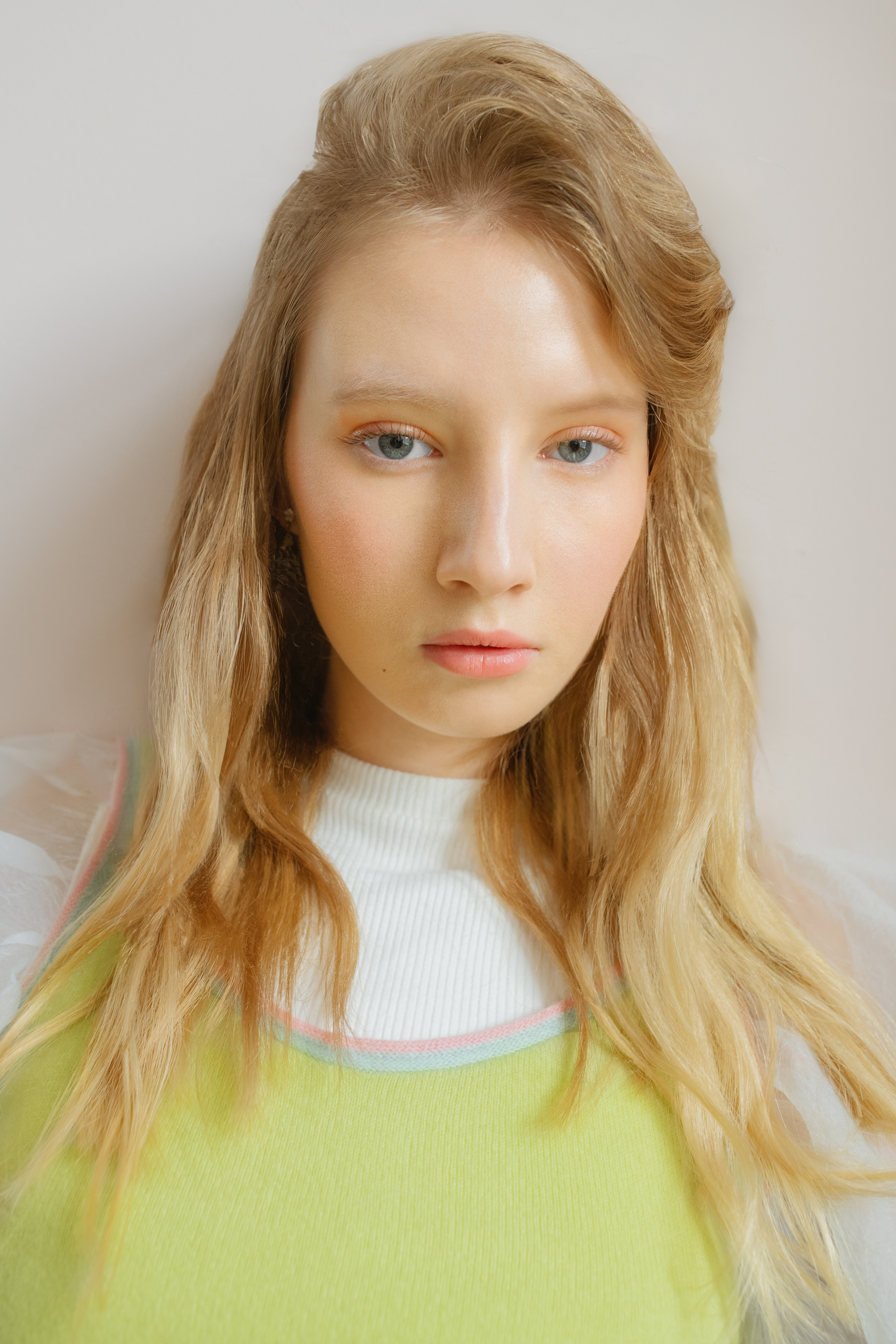 shot of a woman with glass skin, wearing a green sweater and a white shirt.