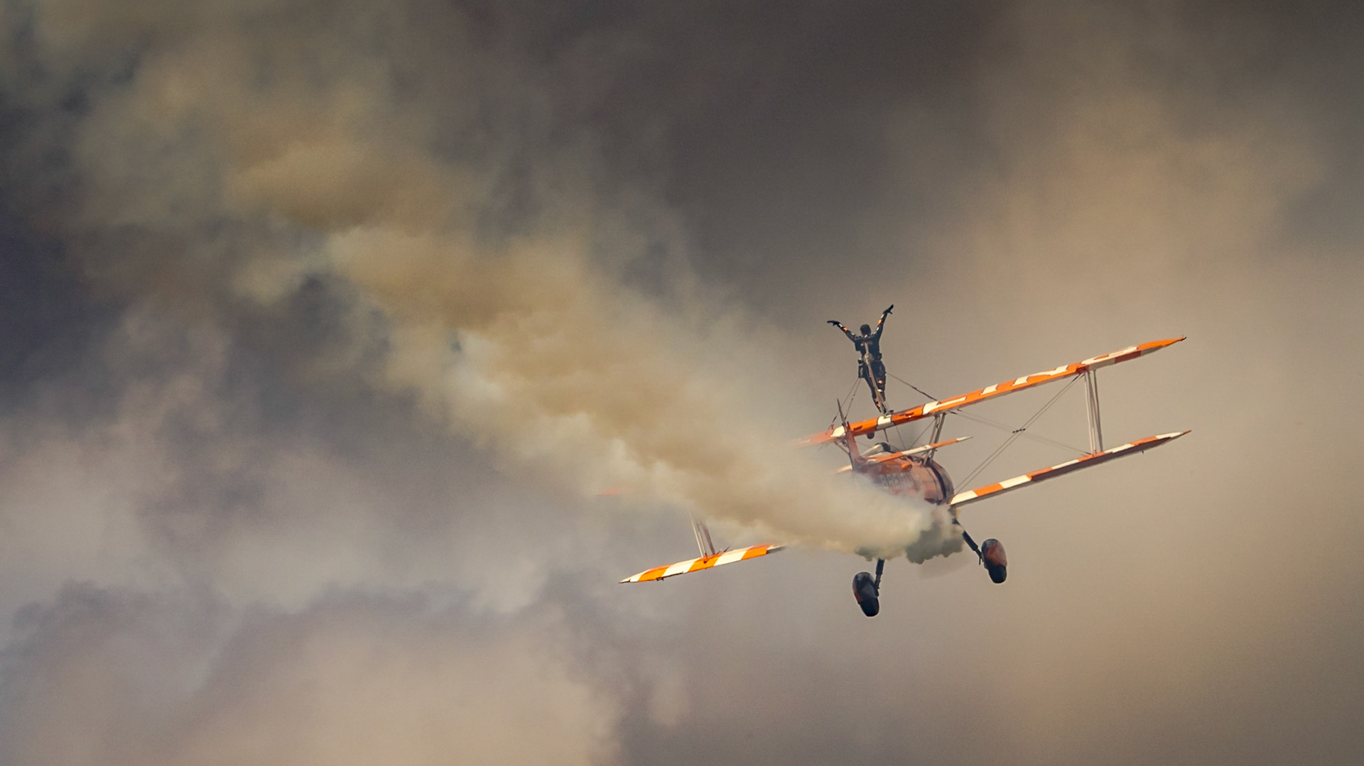 Farnborough, UK - 16th July 2016: A Breitling Team wing walker flies through the smoke trails.