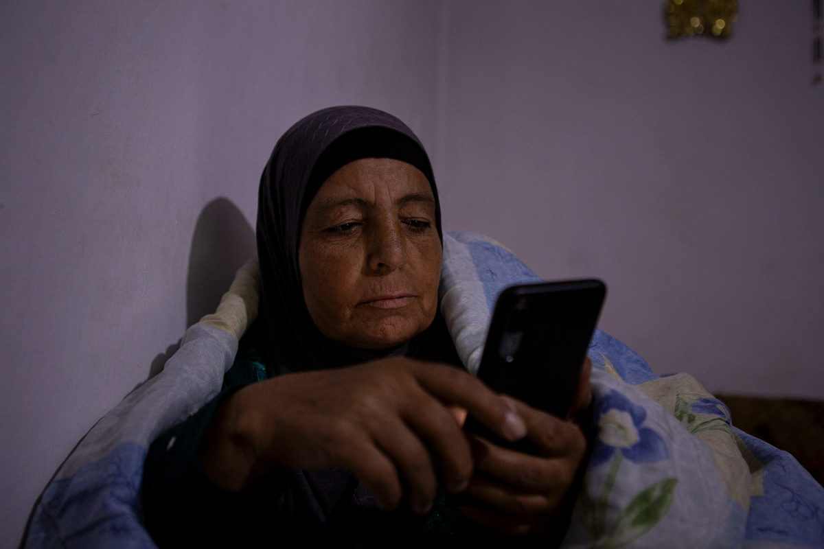 Fatma looks at the news from Syria on her phone after a day of working in the greenhouses. This has become a nightly ritual since the fall of Assad. (12/16/2024)