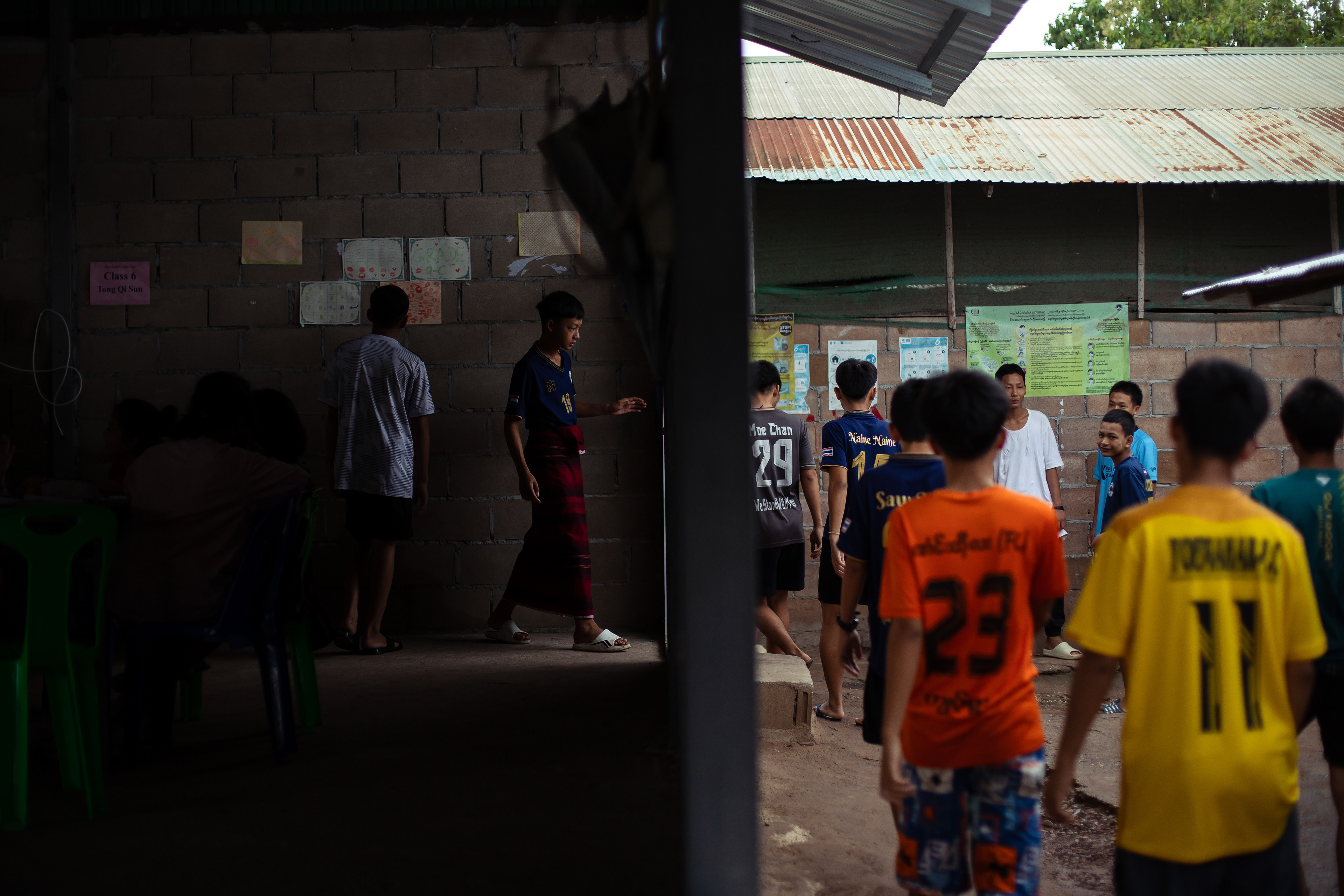 Children walk between makeshift classrooms at KKB School after a short break. The school operates on charitable donations and modest fees, though many families are unable to pay. As a result, teachers often go without salaries, and essential resources are limited. Without sustainable funding, many migrant schools face the risk of downsizing or closure. In early 2025, KKB School was forced to relocate and reduce its size due to a significant drop in donations. July 2024