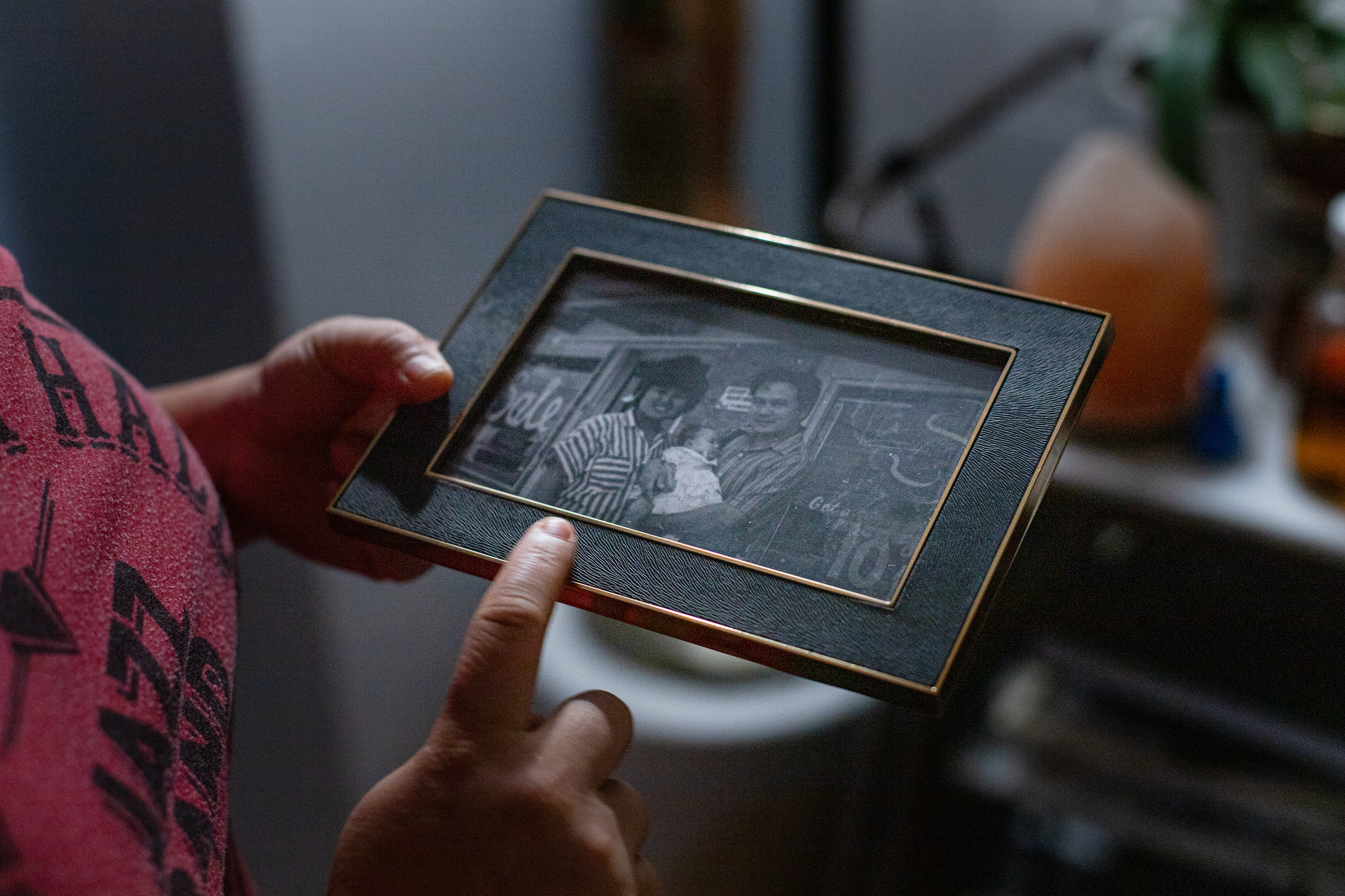 In Anh Luu's home, she holds a family picture of her mother and father in front of the store her father used to own. In 2005, her father's store was destroyed by Hurricane Katrina and her family were displaced. They then moved to Oregon.