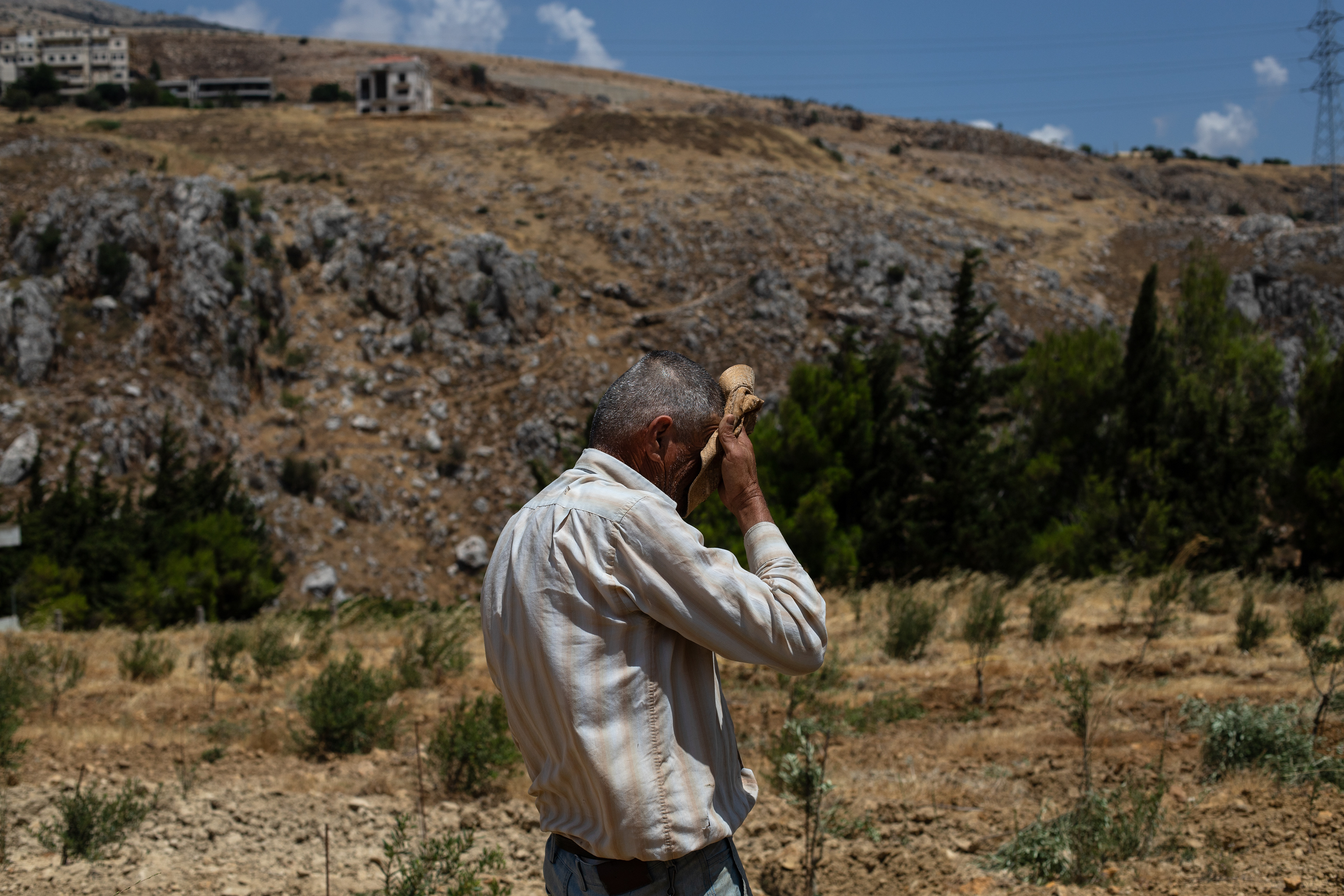 Gabriel, a Lebanese farmer in the Beka Valley wipes the sweat from his head after working on his farm, Lebanon. (July'24)