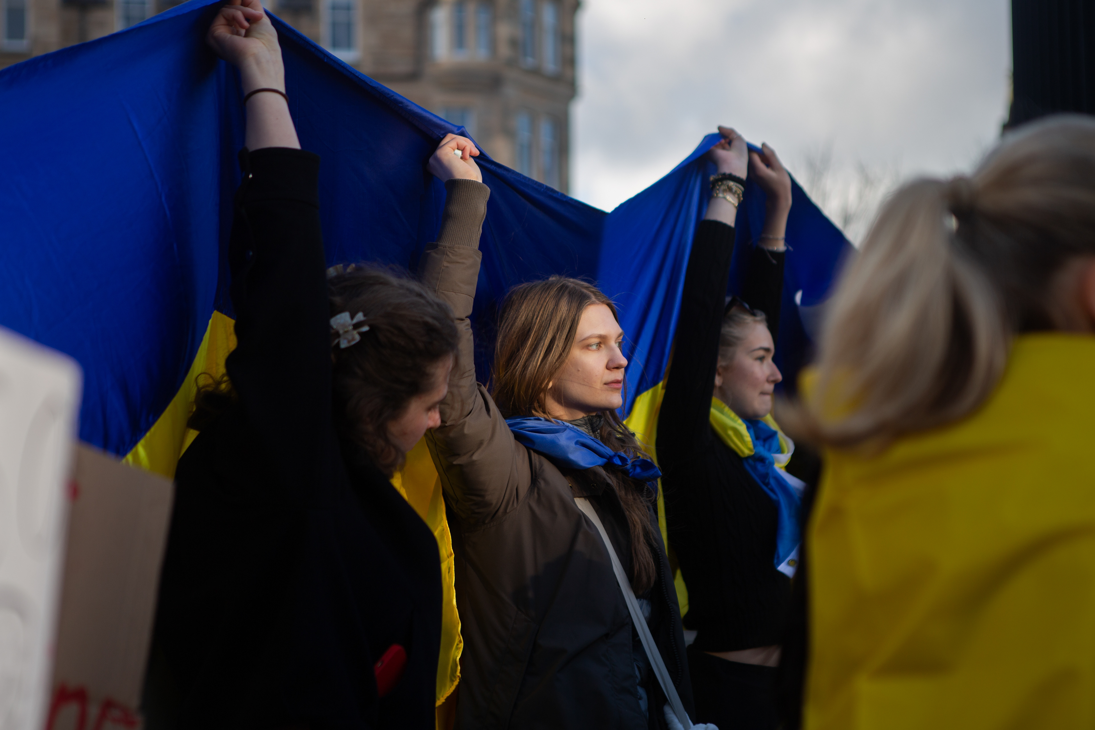Netishyn, a student from Ukraine visiting Edinburgh University joins other students and activists holding a vigil in Bristo square. She joins students holding a Ukrainian flag for a press photo opportunity as they try to bring more attention to Ukraine, Edinburgh. (Feb'25)