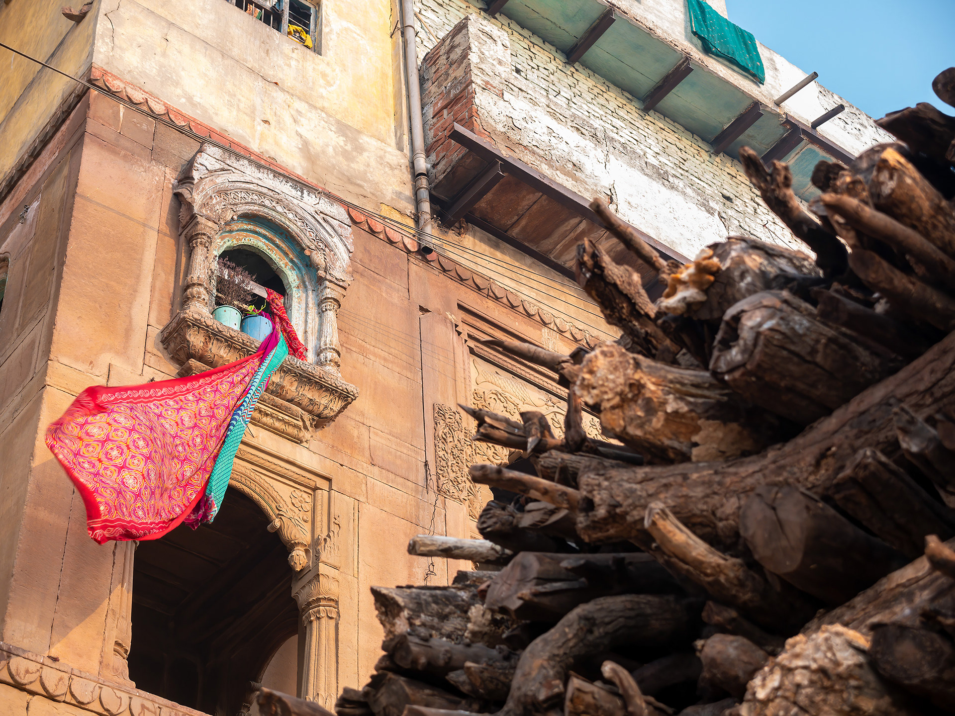 Scarf flowing in the wind above a pile of wood for the nearby funeral pyres in Varanasi, India {030517_Varanasi_946}