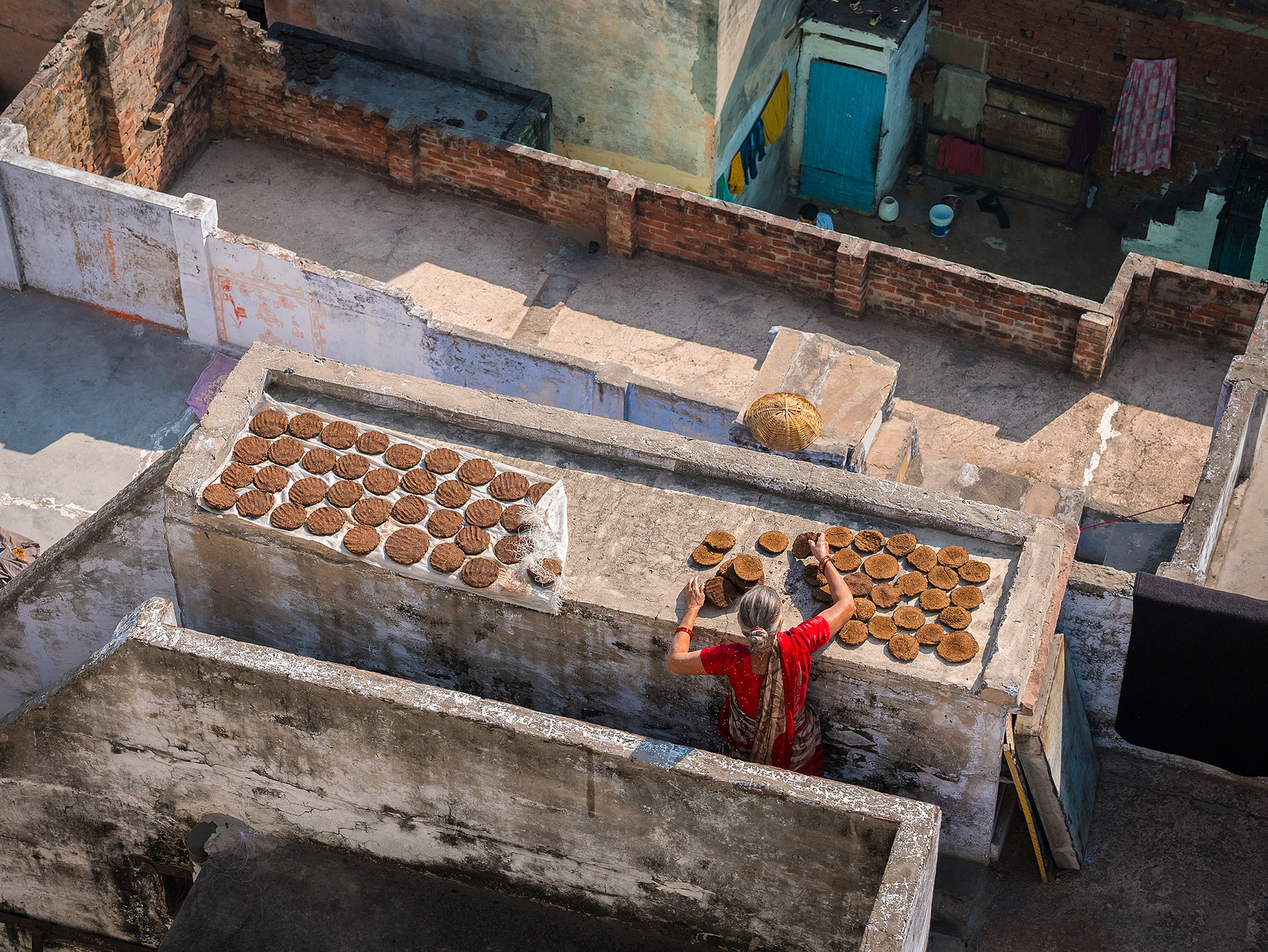 Woman making dung cakes on a rooftop in Varanasi, India {030517_Varanasi_525}