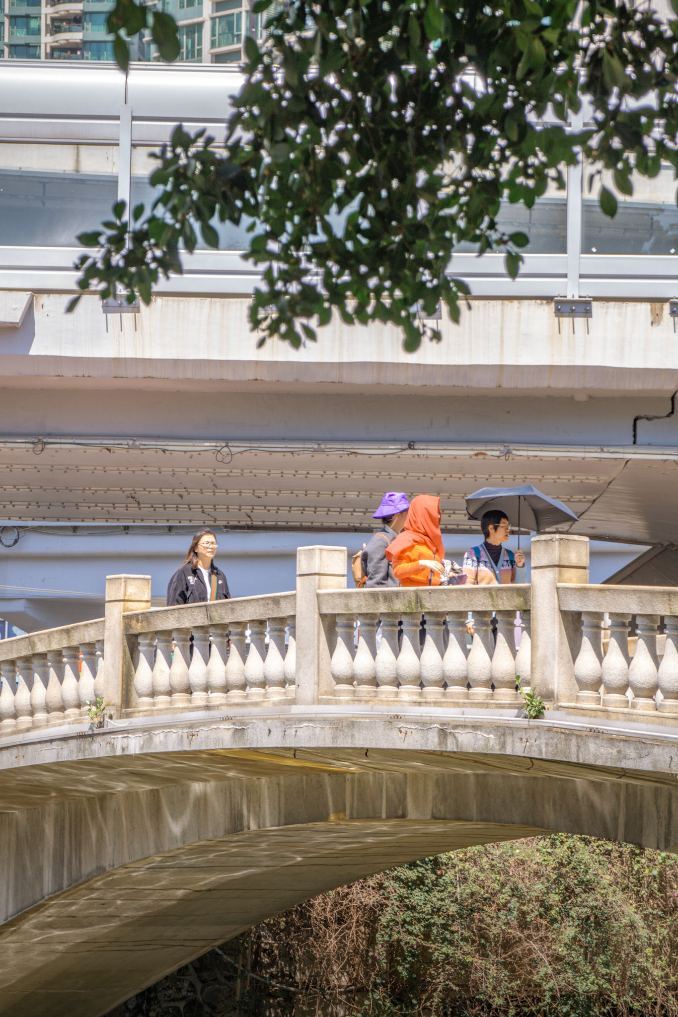 Menschen auf moderner Brücke vor kolonialer Kulisse