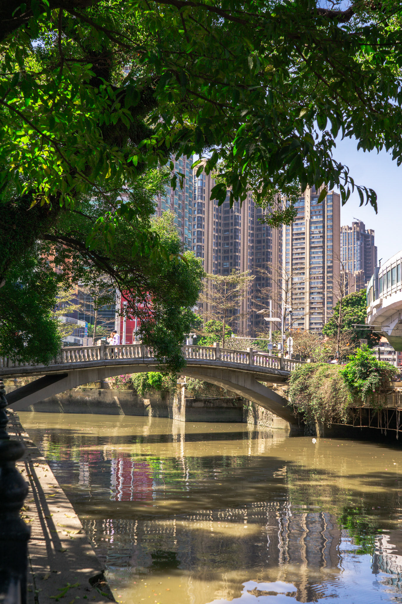 Brücke und Bäume spiegeln sich ruhig im Wasser