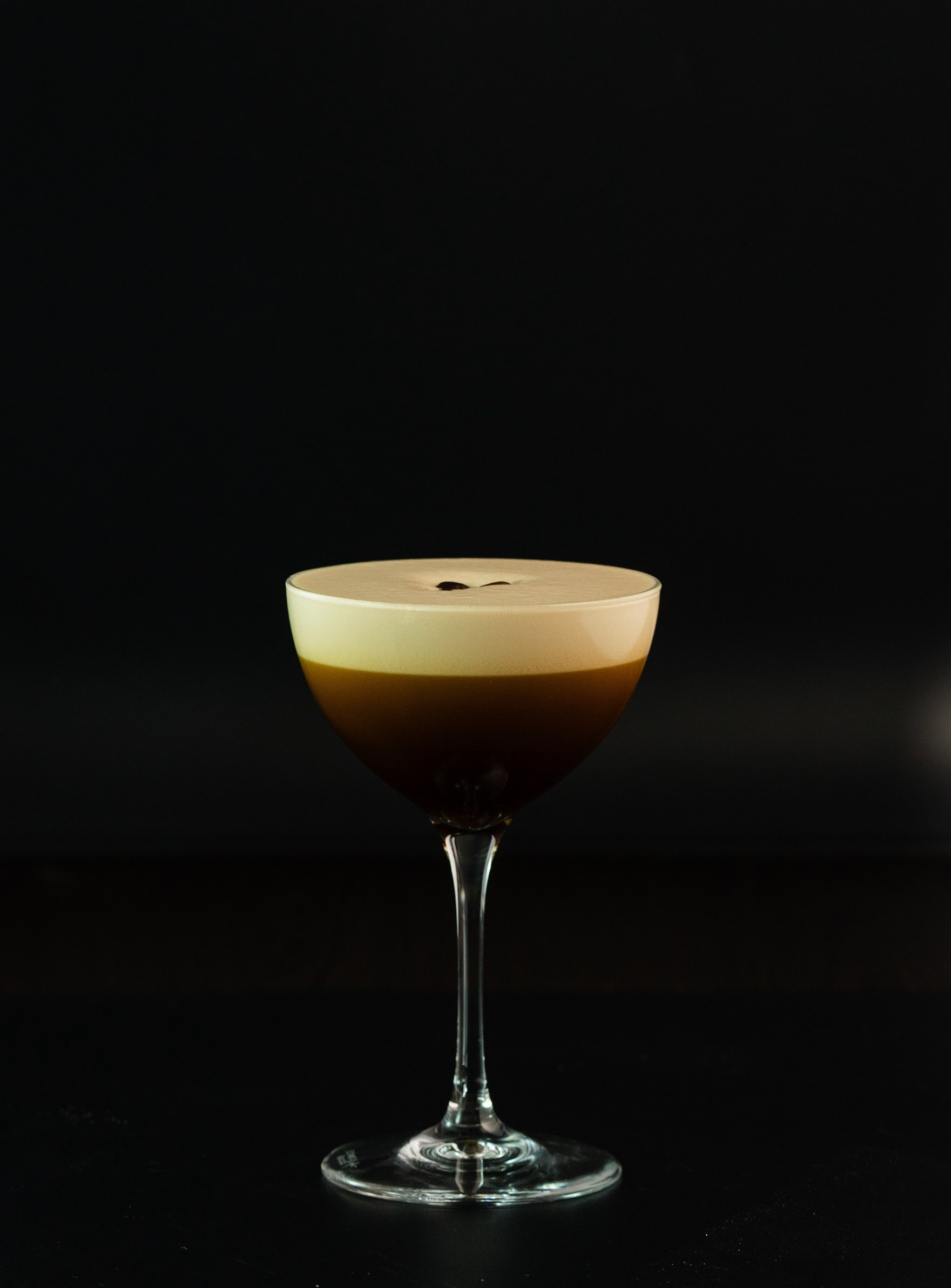Espresso Martini, stilvolle Drinkfotografie mit dunklem Hintergrund und Spiegelung.