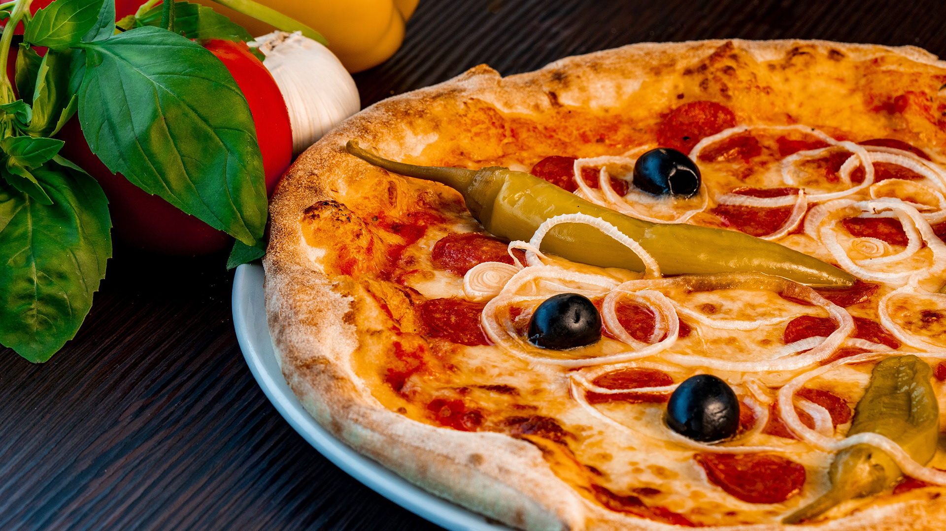 Pizza mit Oliven und Paprika, rustikale Foodfotografie mit kräftigen Farben.