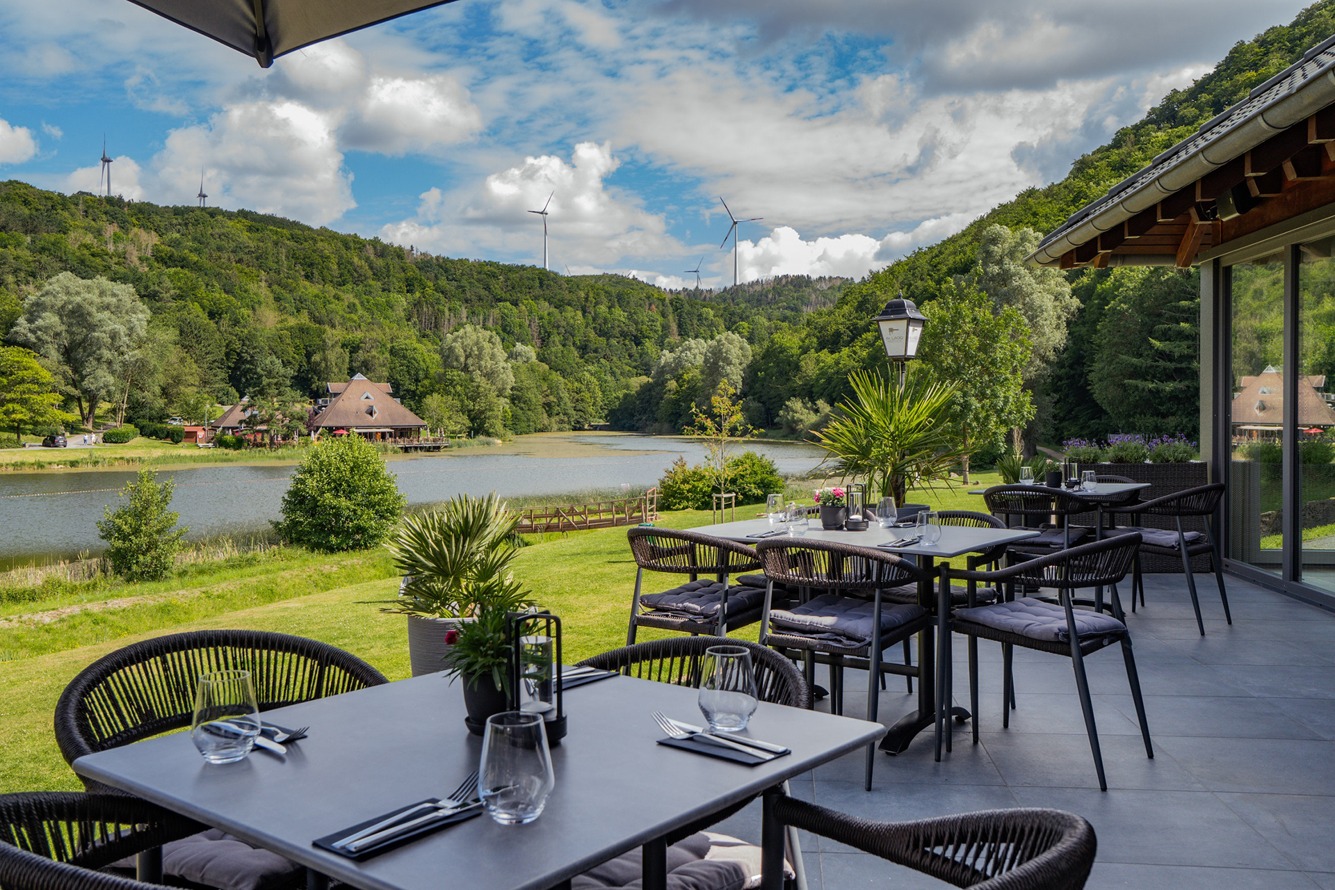 Panoramaaufnahme einer Restaurantterrasse mit Ausblick über Landschaft und See.
