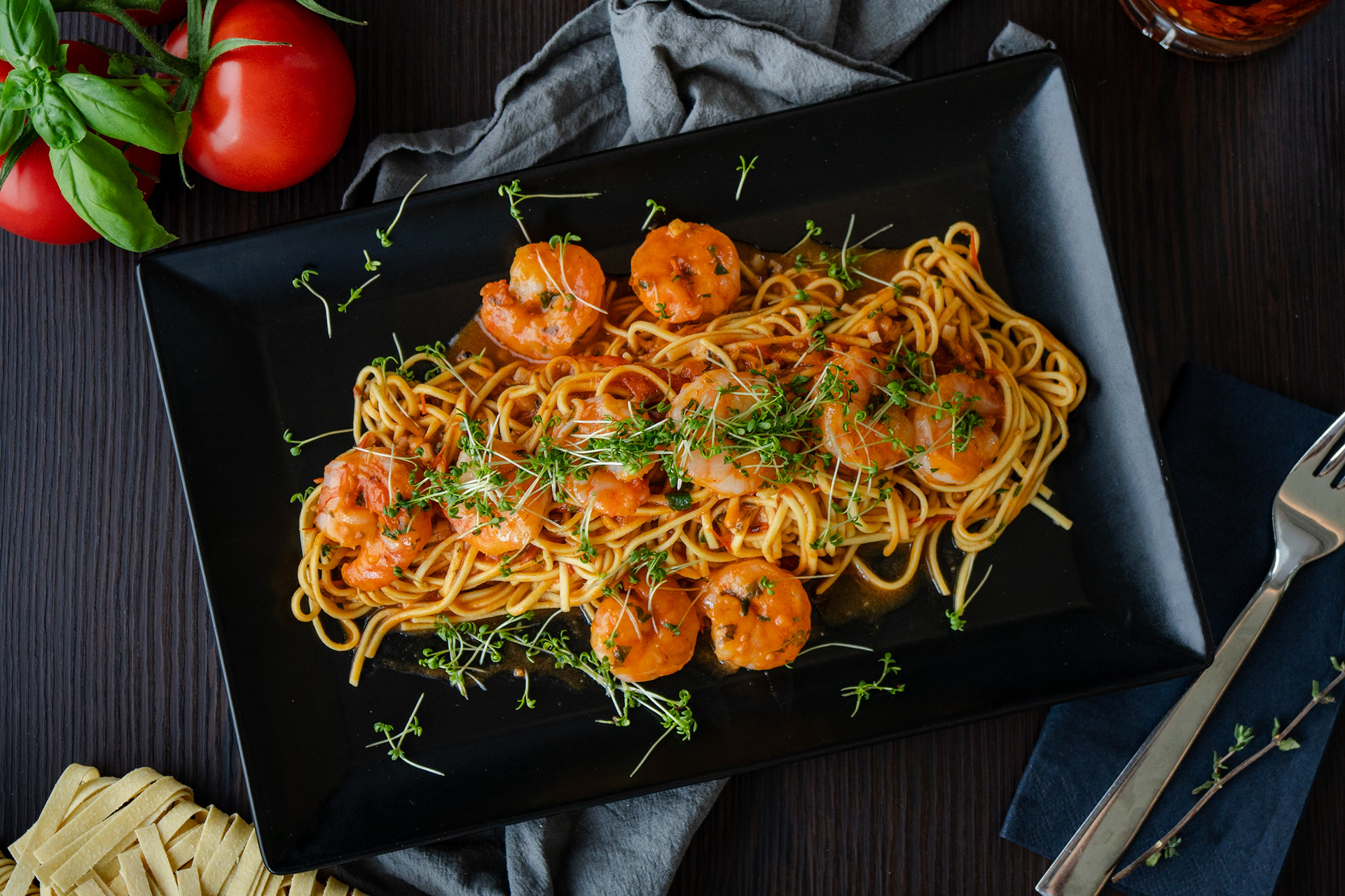 Spaghetti mit Garnelen in Tomatensauce, inszeniert mit natürlichem Licht und mediterraner Farbwelt.