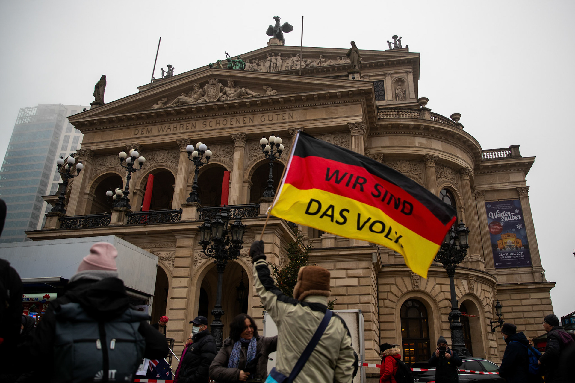 A protester waves a Germany flag with the inscription ' We are the people' during a protest against the requirements to fight the covid pandemic in front of the Alte Oper opera house in Frankfurt am Main, Germany, 04 December 2021.