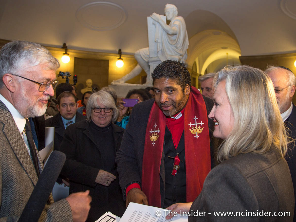 Kim Genardo, communications director for Gov. Pat McCrory, receives petition calling for a special legislative session from N.C. NAACP president Rev. William Barber, center, and George Reed, of the N.C. Council of Churches, on Tuesday, Nov. 26, 2013.