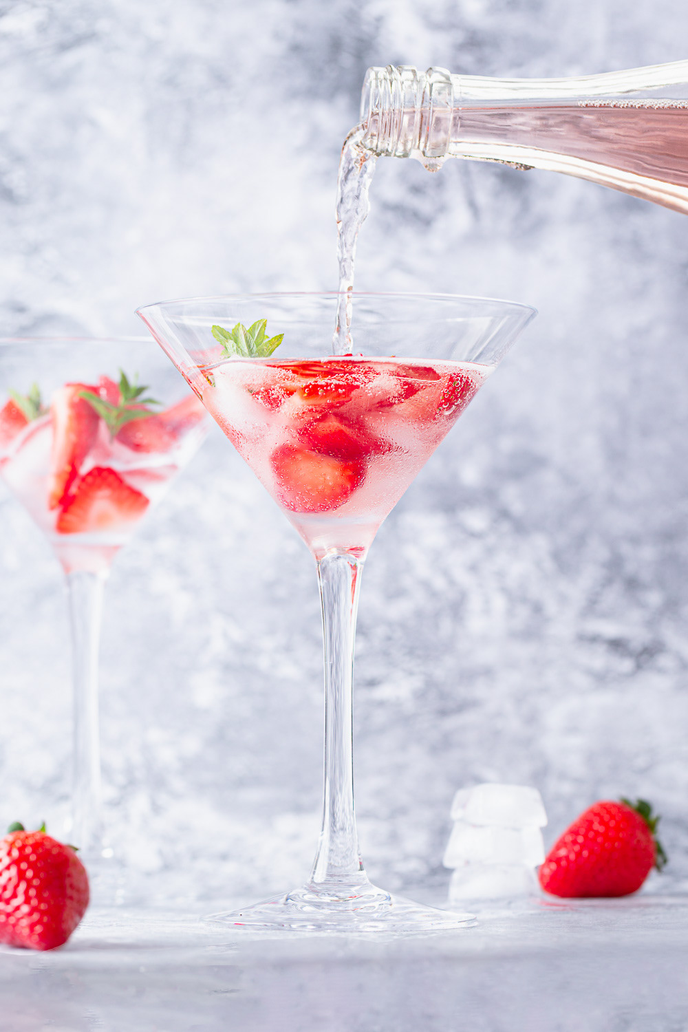 Sparkling rose wine poured to a martini glass and strawberries on the side