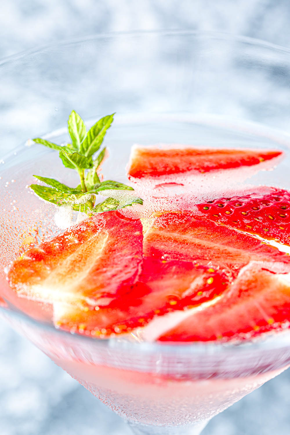 Macro shot of rose wine in a martini glass with strawberries