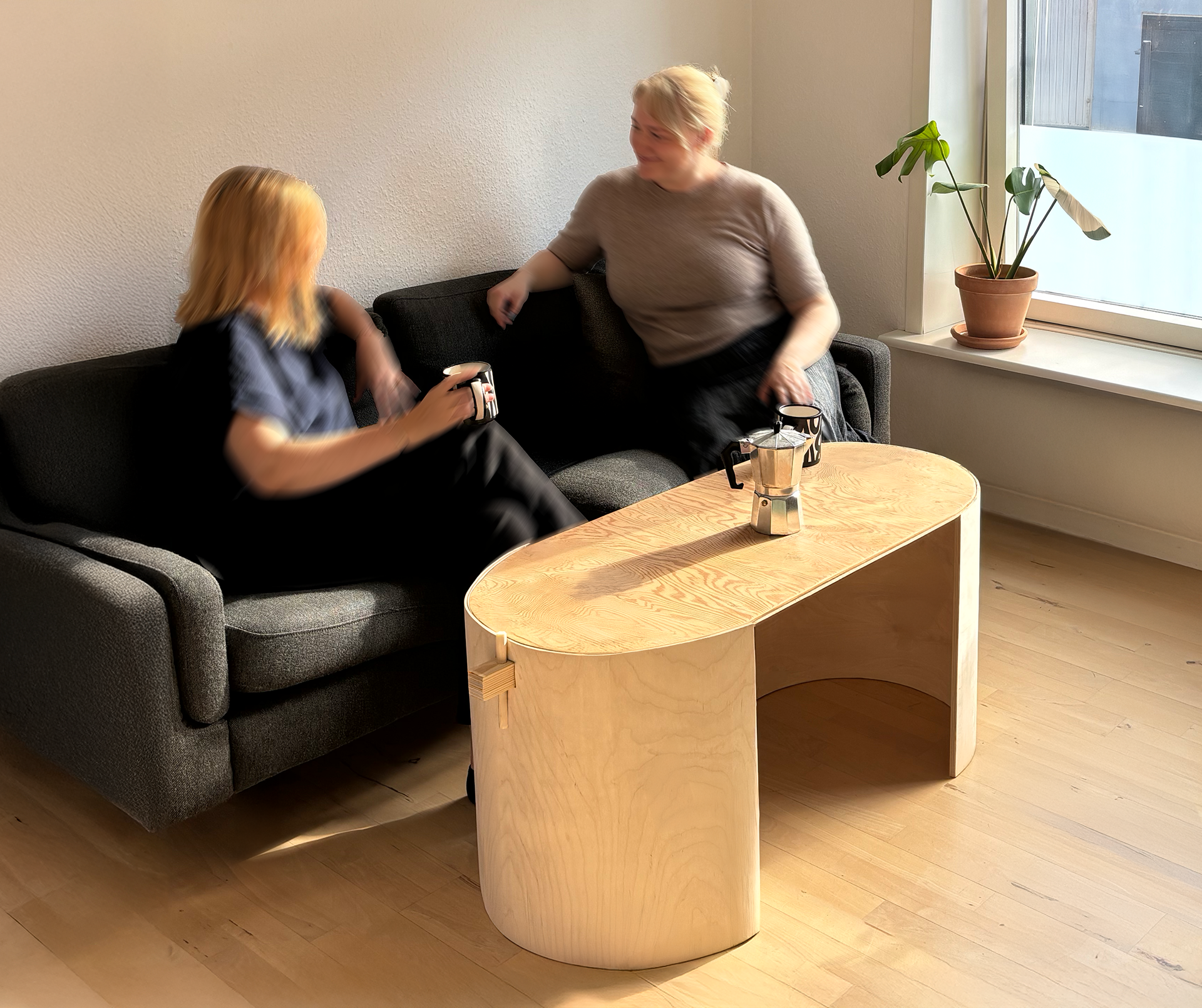 Hug Coffee Table Designed in Context with People in Living Room – Designed by Sarah Eriksen