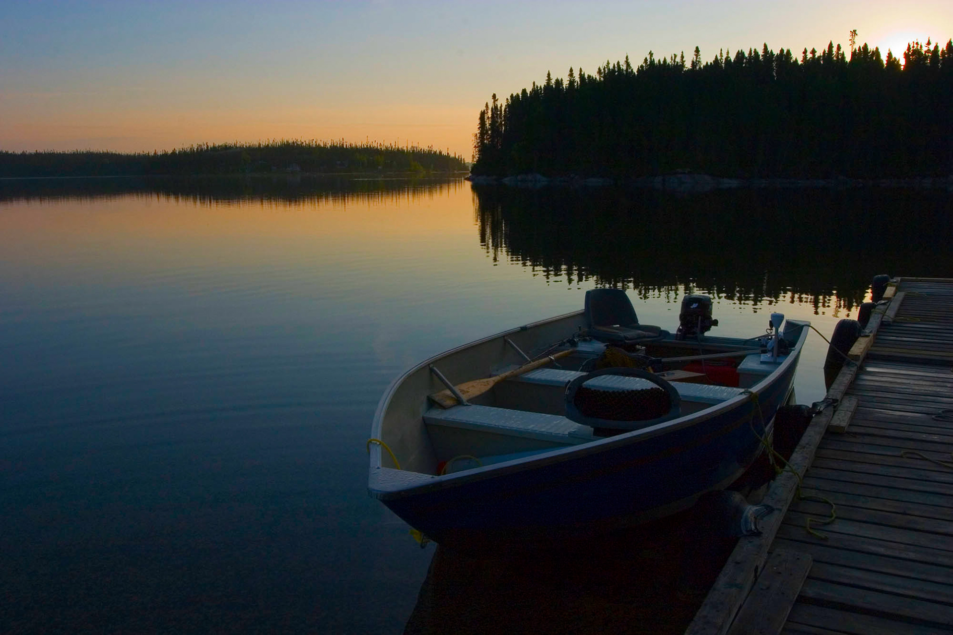 Boat waiting to start a day of fishing as the sun is coming up in Quebec by Guy Sagi