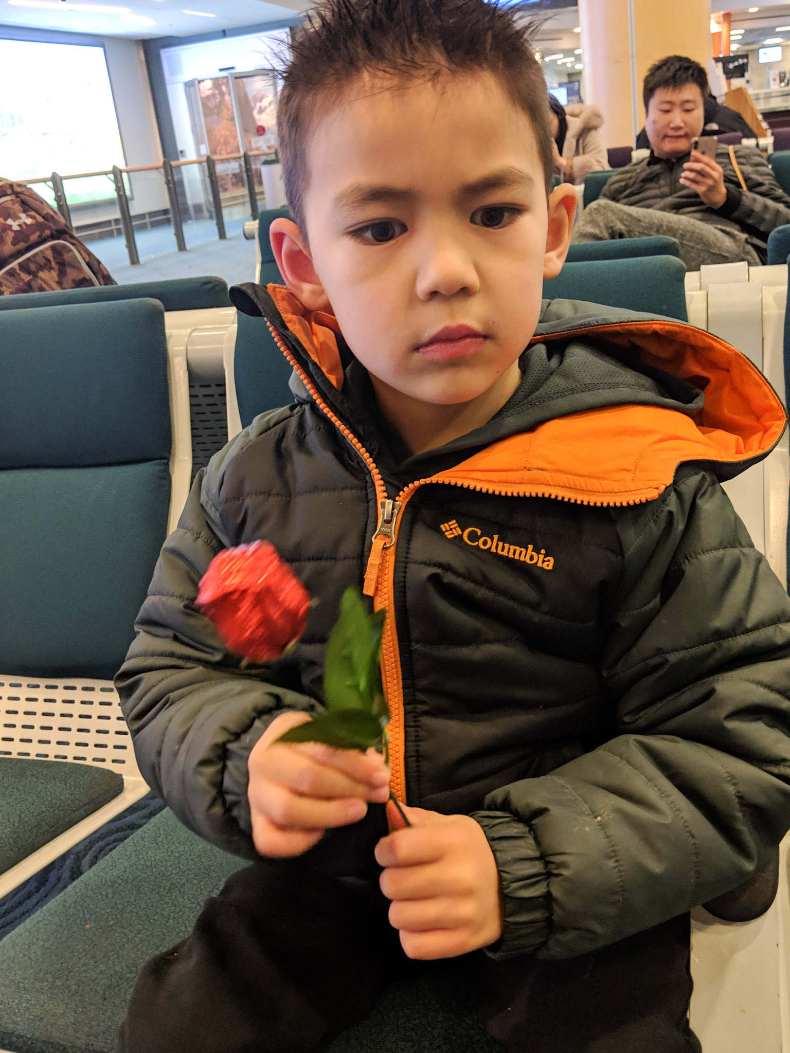 Waiting with a chocolate rose for Mommy at the airport.