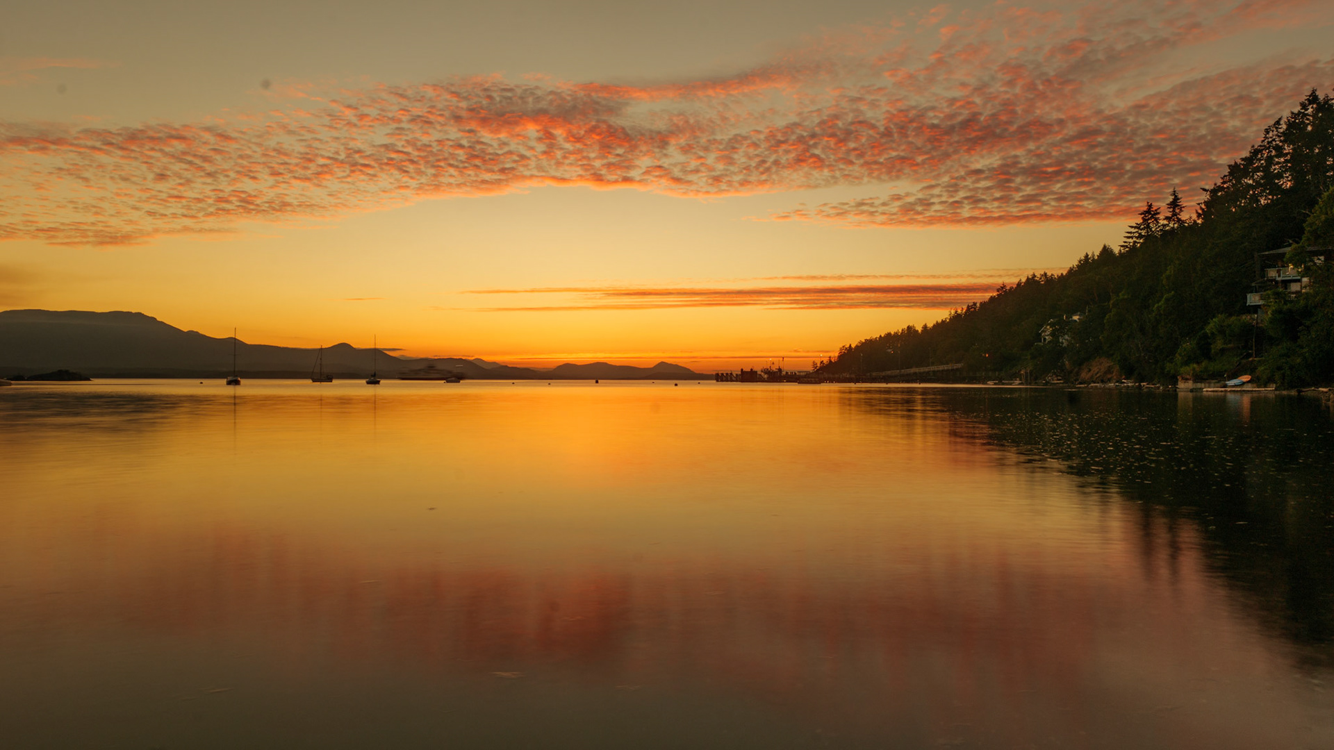 The suns final rays light up the clouds at Vesuvius bay on Salt Spring Island, British Columbia, Canada