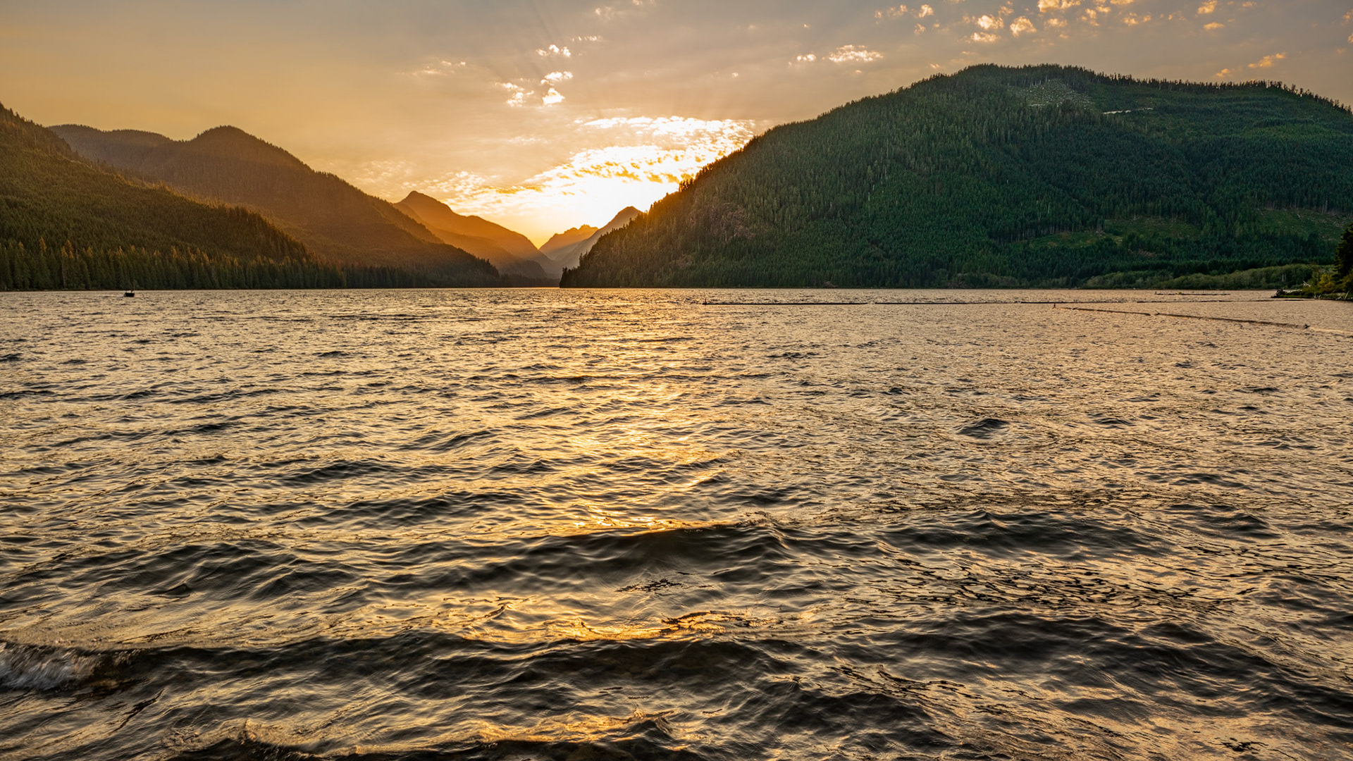 The sun setting behind the mountains at Muchalat Lake near Gold River on Vancouver Island, British Columbia, Canada.
