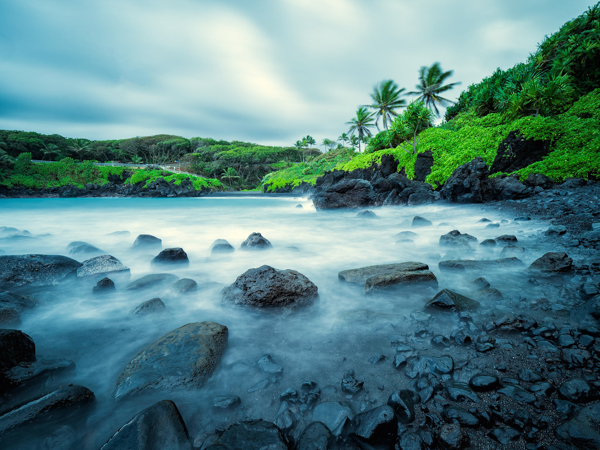 This photo is from Waianapanapa State Park in Maui, Hawaii, which is just outside of Hana. Waianapanapa which literally means glistening water in Hawaiian. The pitch black basalt rocks are beautiful as the waves crash against them. I took this photo just a short walk away from black sand beach which can be seen in the distance.