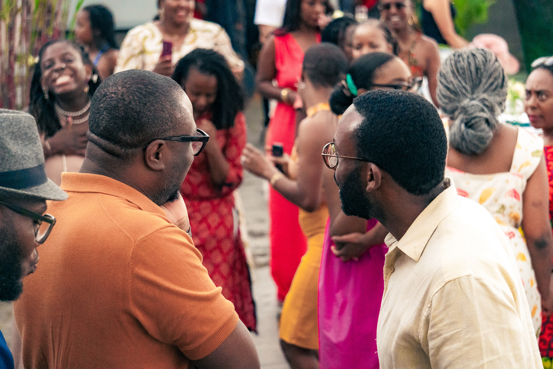 Two men chatting on a rooftop in Nairobi, Kenya, while a crowd is dancing at the background