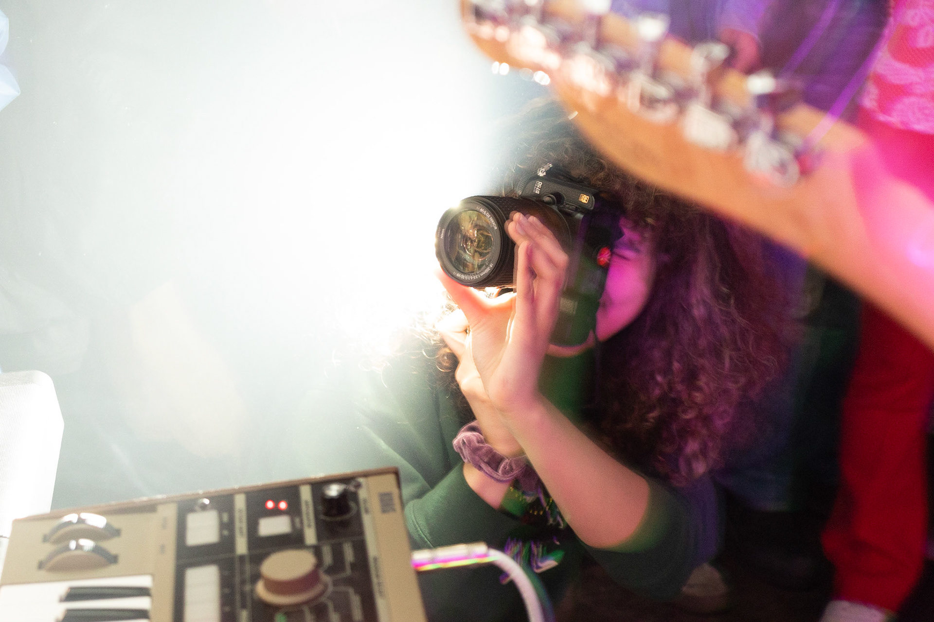 Maddi Brown takes pictures at a  concert  hosted by The Harrison, a student run music venue hosted in the basement of a Sumner residence. Images taken the night of 3/04/22. The Nikon flash built into Maddi's camera goes off as she takes a picture of the pianist.