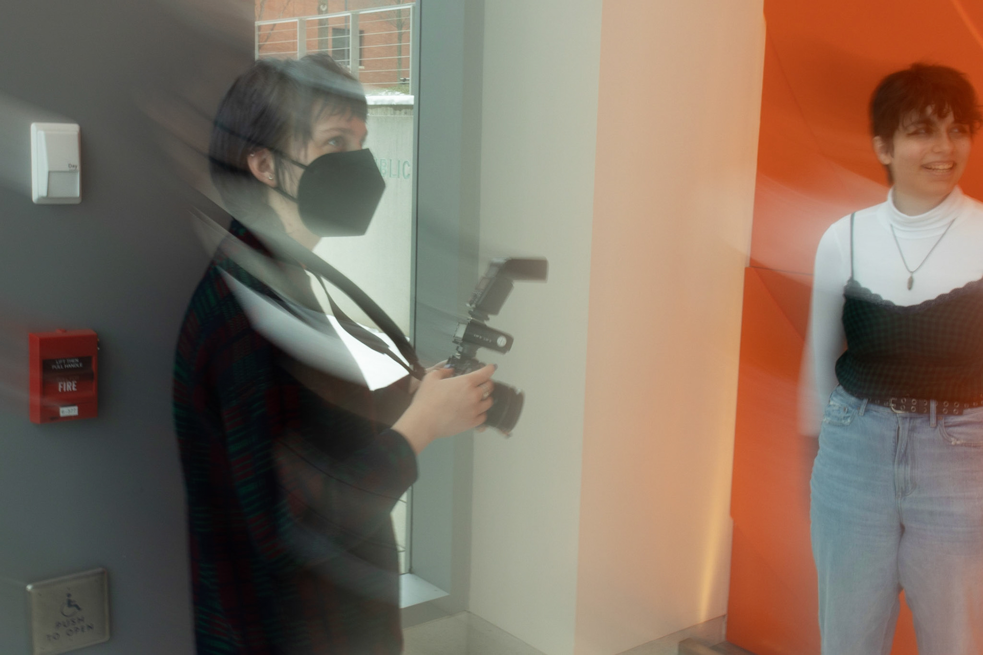 Em Burris captures images of Grey around Newhouse for their LGBTQ+ Fashion Project. Images taken 03/30/22. Burris takes a short break from taking pictures to let people pass on the stairs in Newhouse 2.