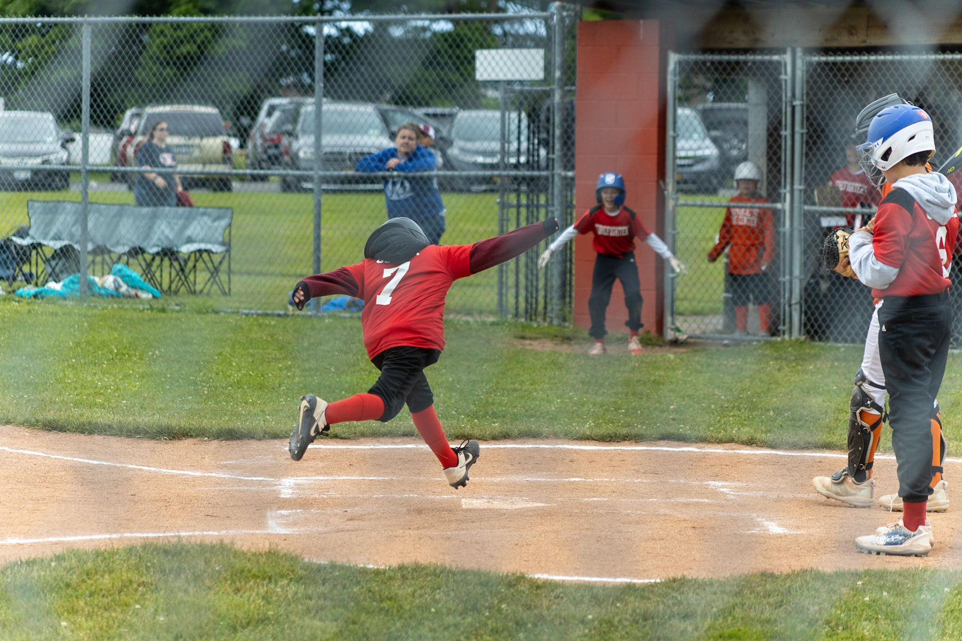 Brody Gosiar (#7) jumps onto home as Firefighter teammates cheer from the dugout during the June 18th game at Lagoe field.
