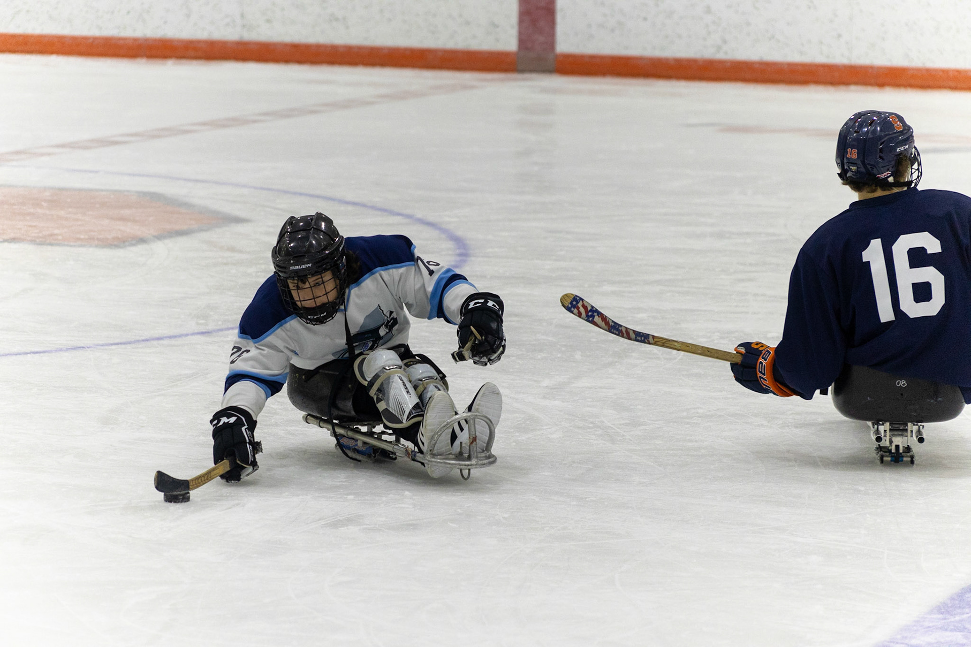 The CNY Flyers, a sled hockey team, played against the Syracuse University Men's Club Hockey team on 11/19/22 at Tennity Ice Skating Pavilion. The game ended with the Flyers scoring 8 to Syracuse 0 with 25 shots on goal by the Flyers compared to Syracuse's 2. While the game was still competitive, it was more for the fun of the sport with smiles shared by all. It was also a new experience for the Syracuse team which consisted of able-bodied individuals who may have never experienced sled hockey. #76, Myles Favata, reaches for the puck as #16. Timothy Cook skates by.