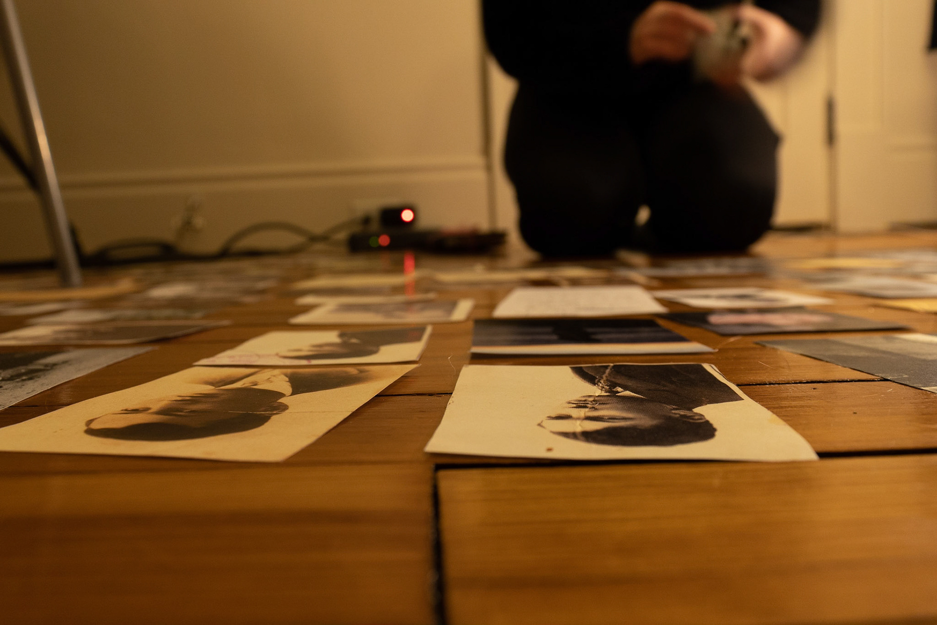 Emily Steinberger captures photos that simulate the layout of a page for her final Honor Thesis Project. The project is focused on conserving Steinberger's family history which was heavily affected by the Holocaust. Taken at Emily's apartment on 04/02/2022. She starts by laying all her photos on the ground around her.