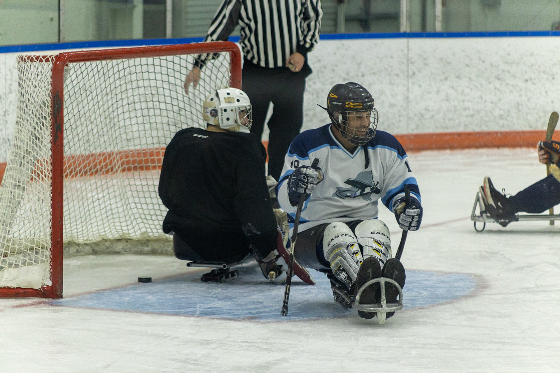 The CNY Flyers, a sled hockey team, played against the Syracuse University Men's Club Hockey team on 11/19/22 at Tennity Ice Skating Pavilion. The game ended with the Flyers scoring 8 to Syracuse 0 with 25 shots on goal by the Flyers compared to Syracuse's 2. While the game was still competitive, it was more for the fun of the sport with smiles shared by all. It was also a new experience for the Syracuse team which consisted of able-bodied individuals who may have never experienced sled hockey. #19 of the Flyers, Jamie Favata, smiles as he pushes away from the goal he just landed a shot into.