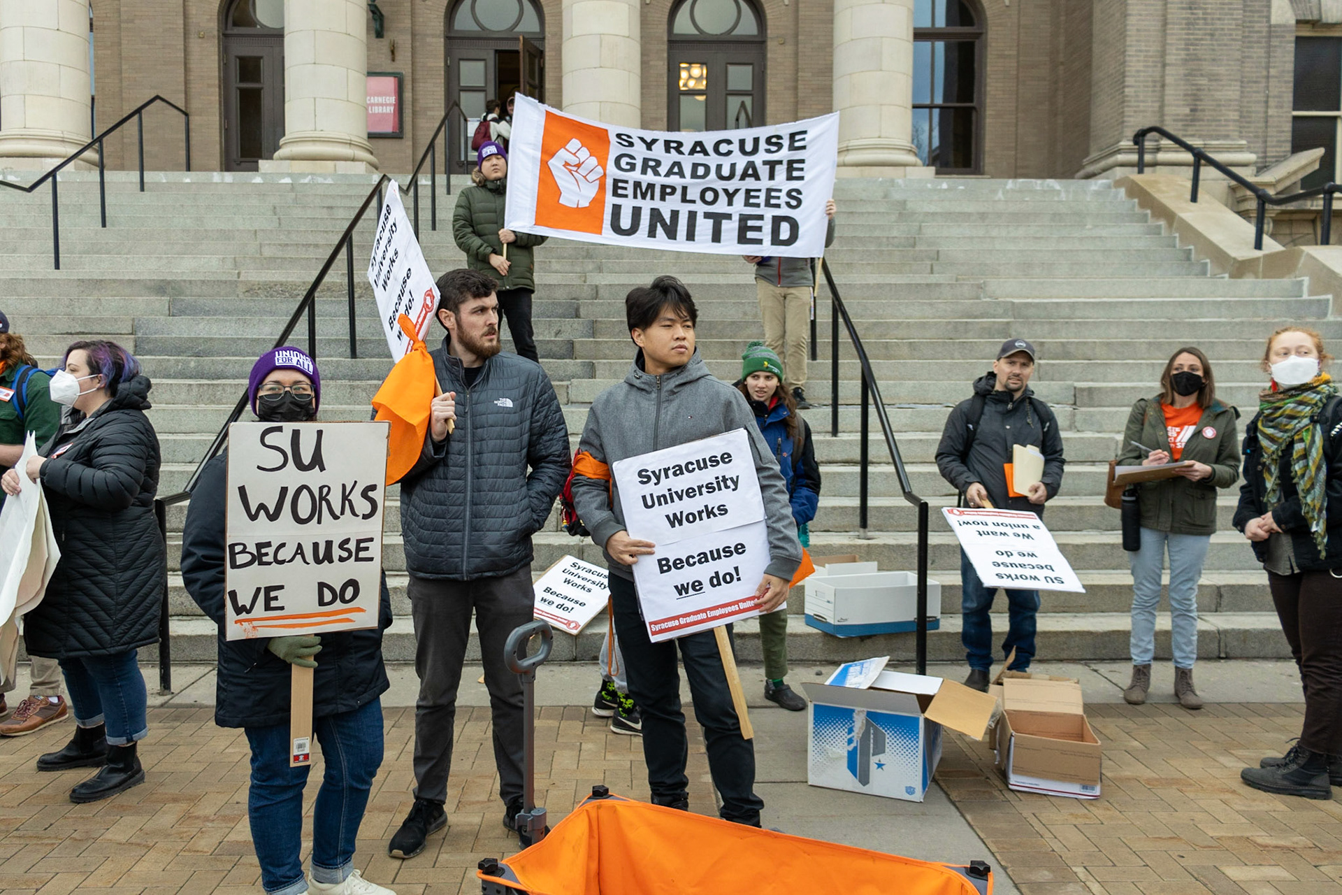 The Syracuse Graduate Employees Union gathered fellow students, supporting faculty and staff, as well as regular observers at the steps of Carnegie Library as they advocated for the University to recognize the union and accept the union's demands. The group then marched to the student center and onwards to the administration building where leaders would meet with the Provost.