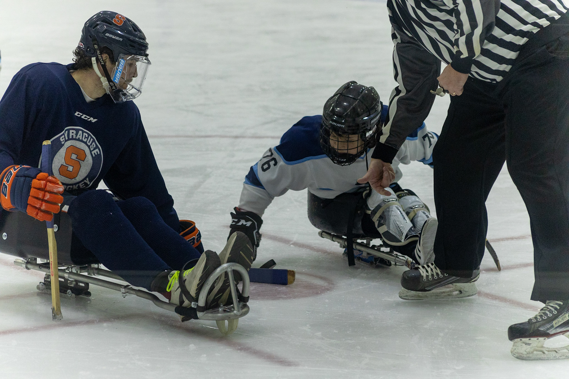 The CNY Flyers, a sled hockey team, played against the Syracuse University Men's Club Hockey team on 11/19/22 at Tennity Ice Skating Pavilion. The game ended with the Flyers scoring 8 to Syracuse 0 with 25 shots on goal by the Flyers compared to Syracuse's 2. While the game was still competitive, it was more for the fun of the sport with smiles shared by all. It was also a new experience for the Syracuse team which consisted of able-bodied individuals who may have never experienced sled hockey. #76 of the Flyers, Myles Favata, plays a critical role for the team by winning the faceoff ensuring Flyers possession.