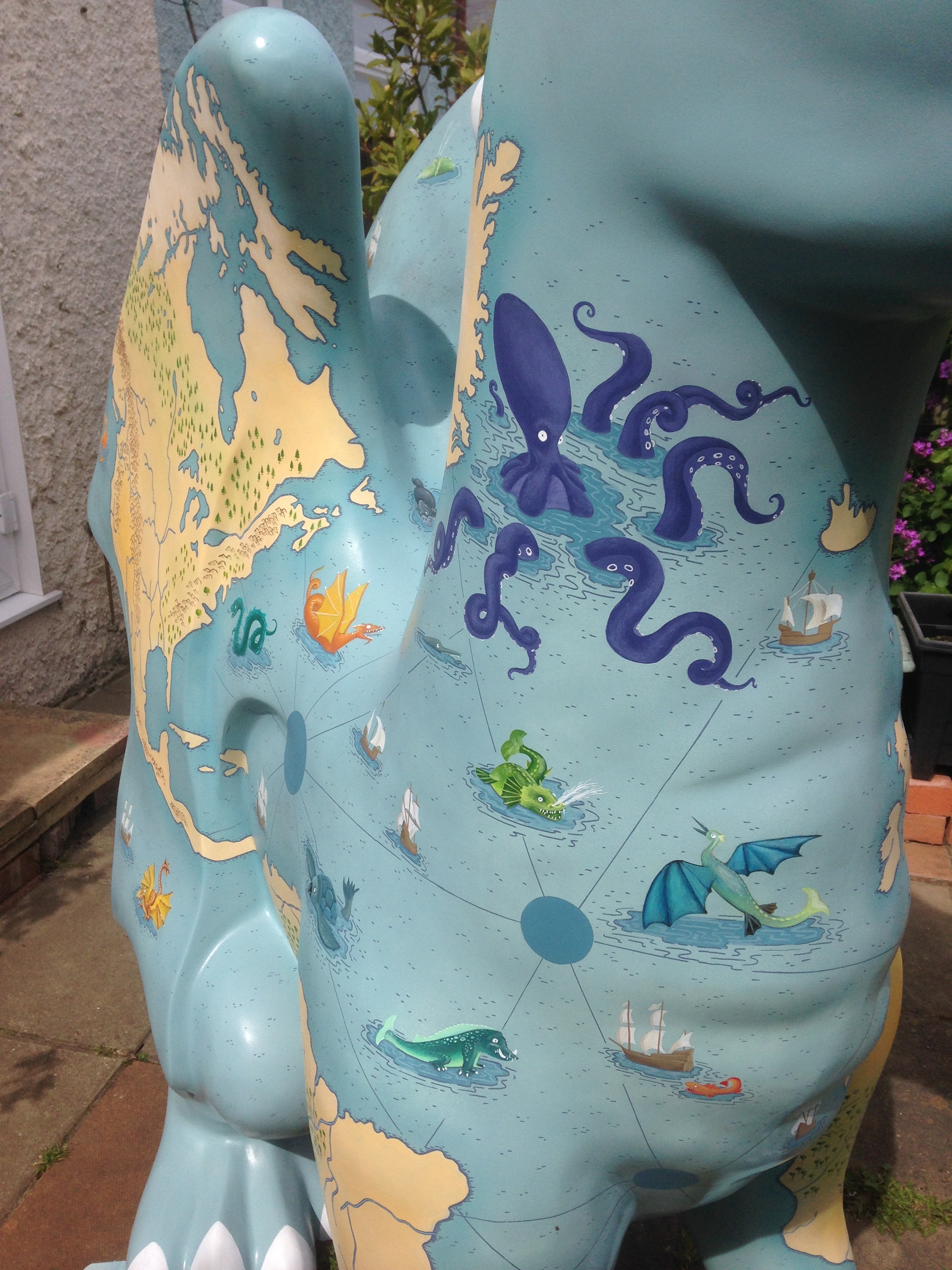 Close up of pained sea monsters on a Dragon sculpture painted with an illustrated map of the world. By Fiona Gowen. Part of the GoGoDragons! Trail in Norwich in 2015