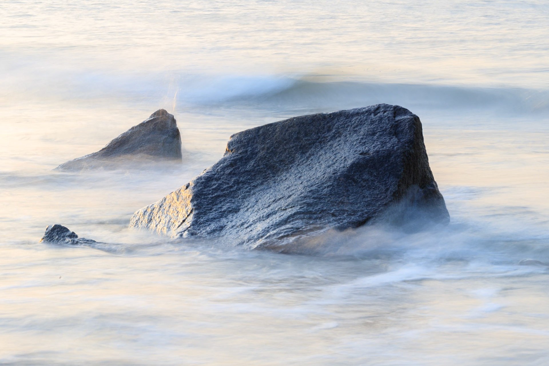 Flowing ocean waves white with foam as they flow over rocky outcrops