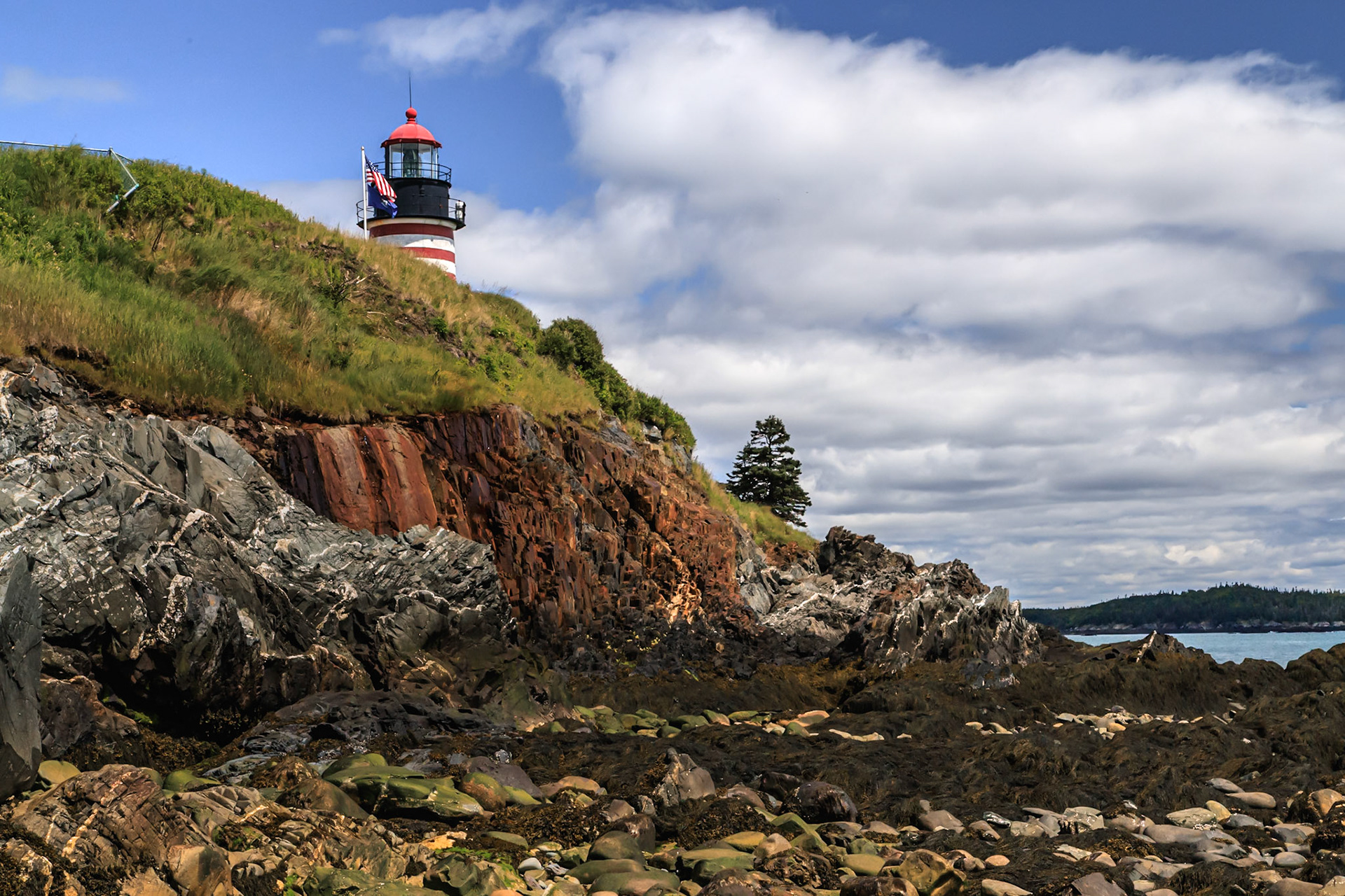 The lighthouse high above on a clift with barren rocky shores below