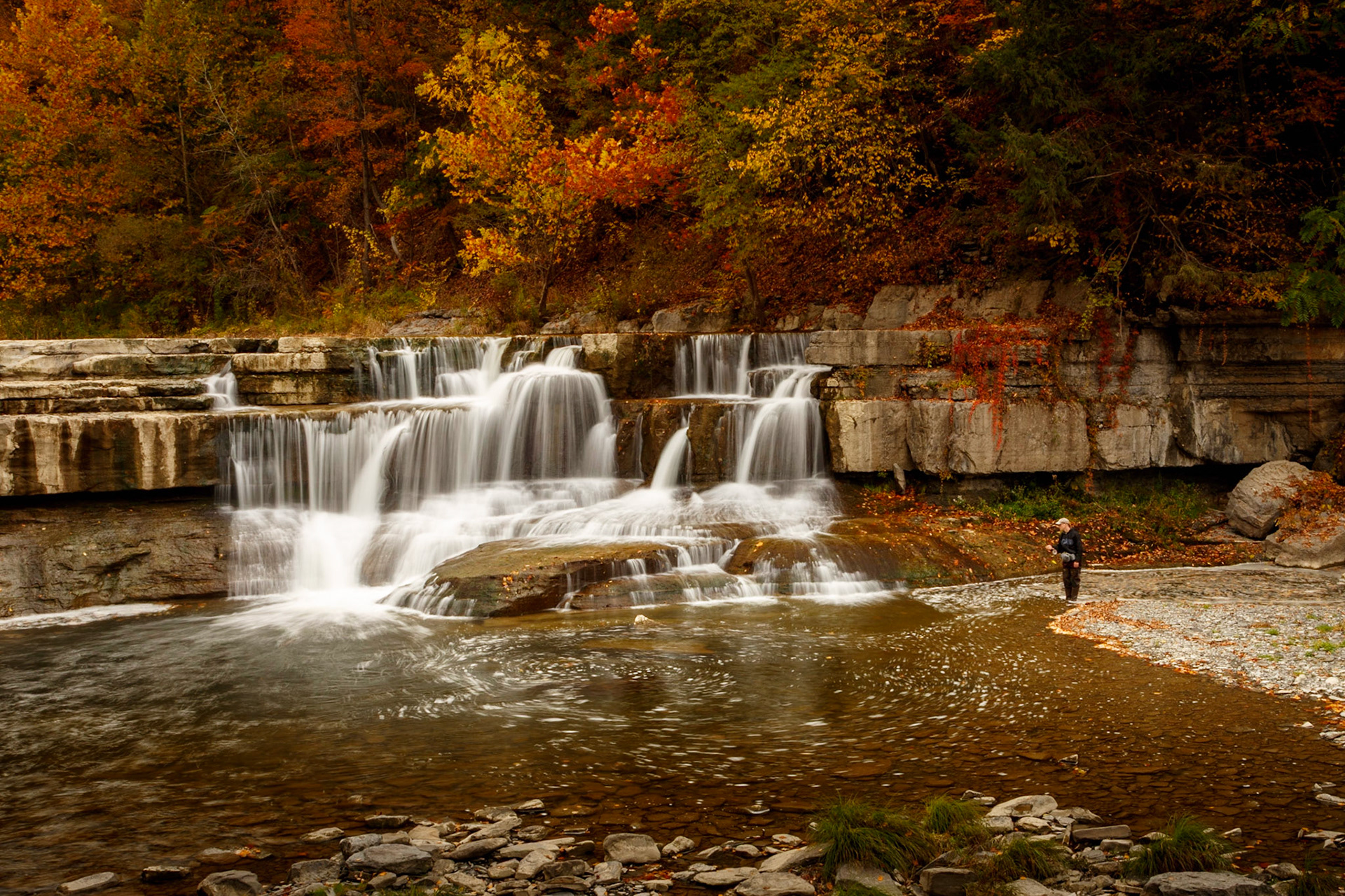 Lone flyfisher man at lower falls in autumn