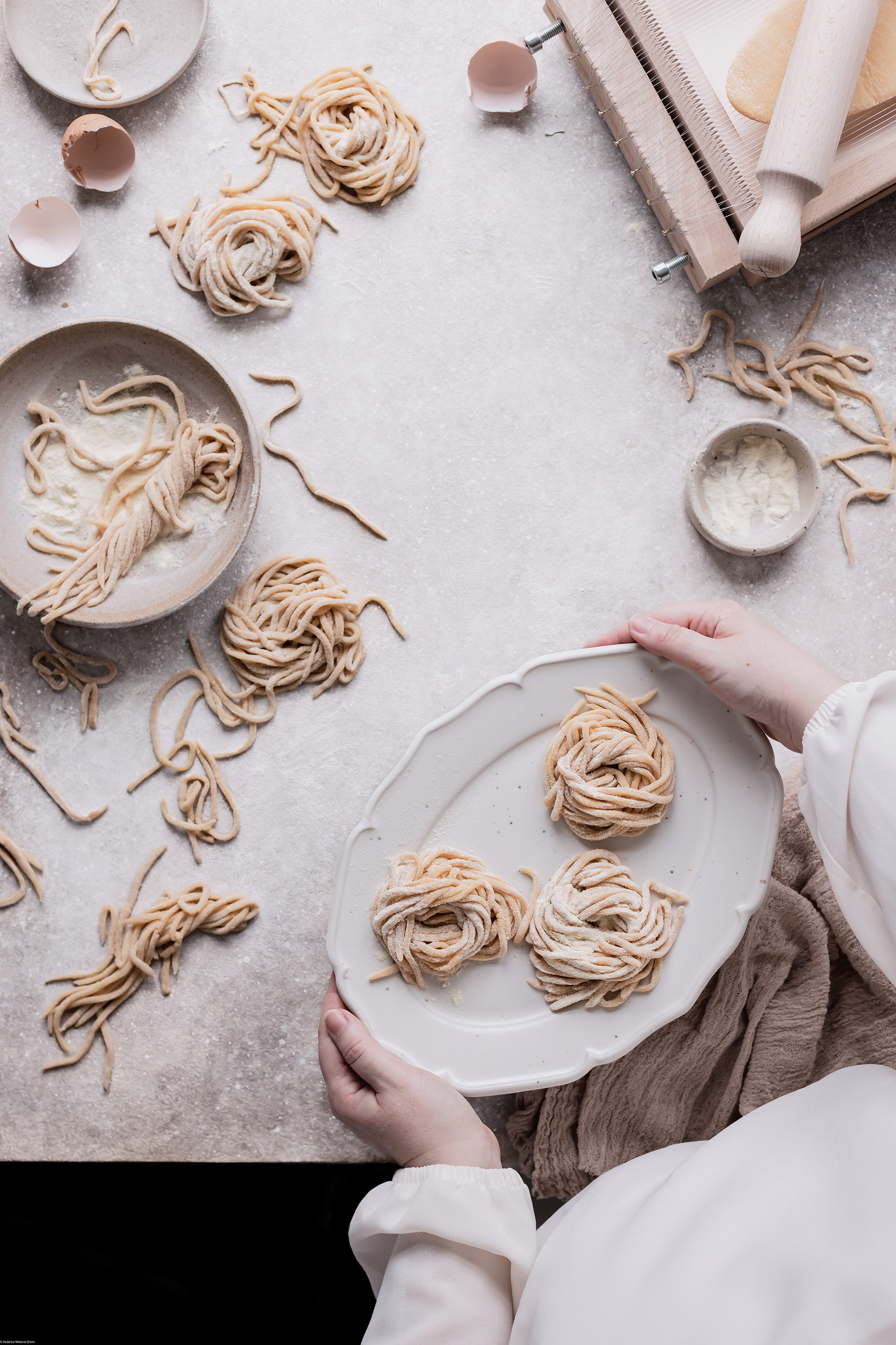 A food photography ( fotografia di cibo) image of hand holding serving plate with some homemade pasta by Federica Melania Orsini - a food photographer ( fotografo di cibo) in Bologna