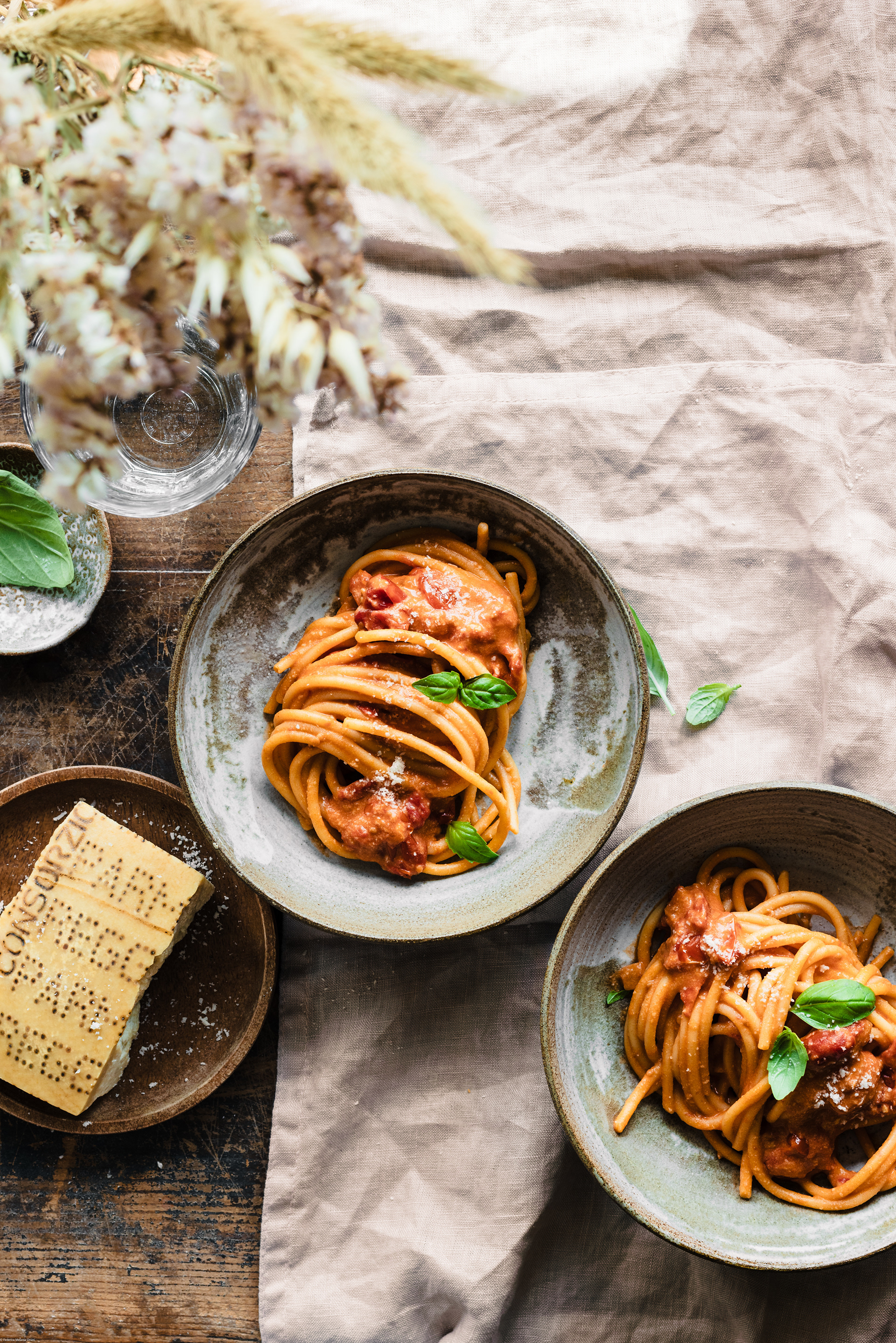 A food photography (fotografia di cibo) image of spaghetti on two bowls with Parmigiano Reggiano cheese on the side made by Federica Melania Orsini - a food photographer (fotografo di cibo) in Bologna.