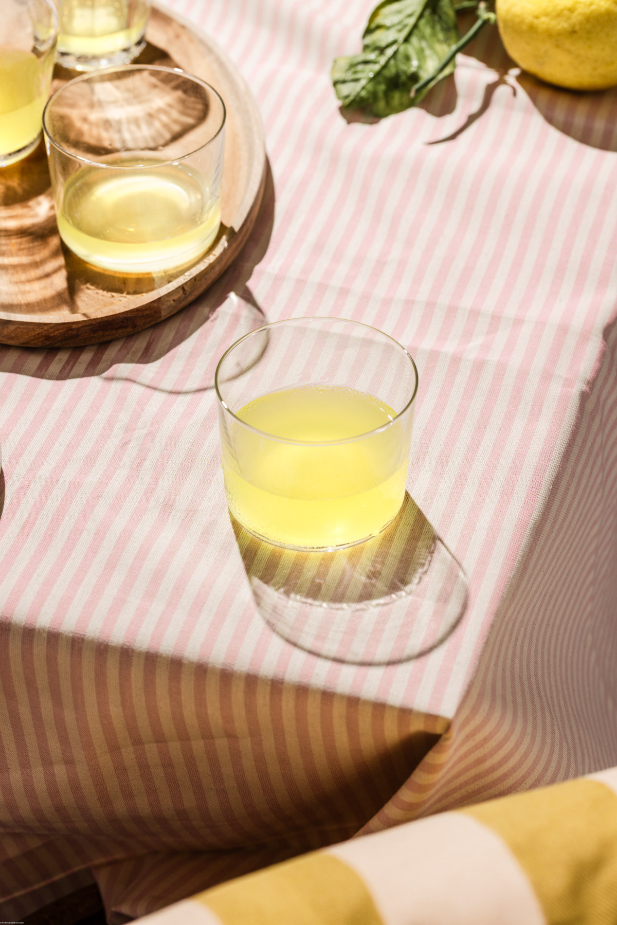 A food photography ( fotografia di cibo) image of limoncello on a stripe tablecloth by Federica Melania Orsini - a food photographer ( fotografo di cibo) in Bologna