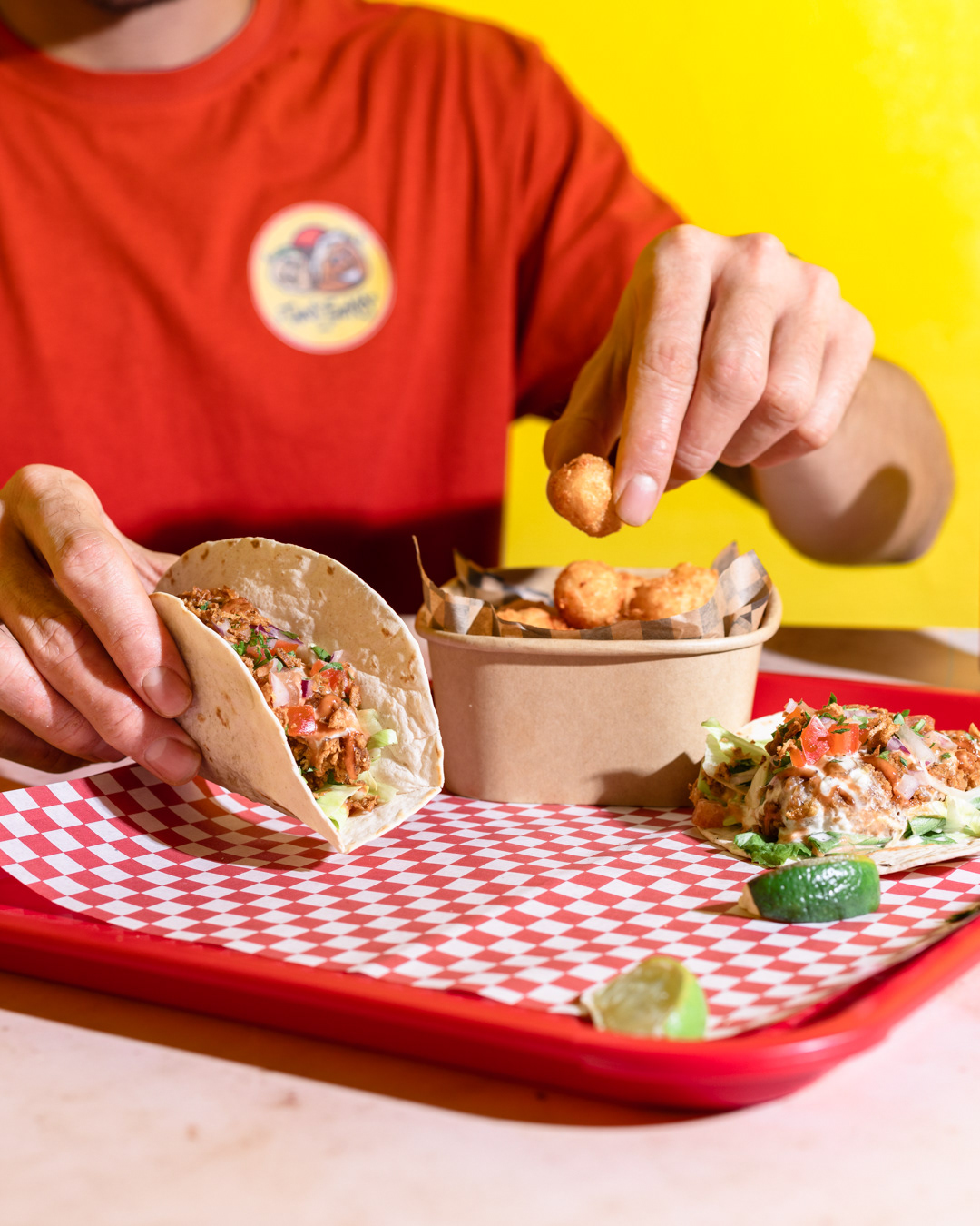 A restaurant photography image of chicken tacos with human holding one tacos made by Federica Melania Orsini - a restaurant photographer in London