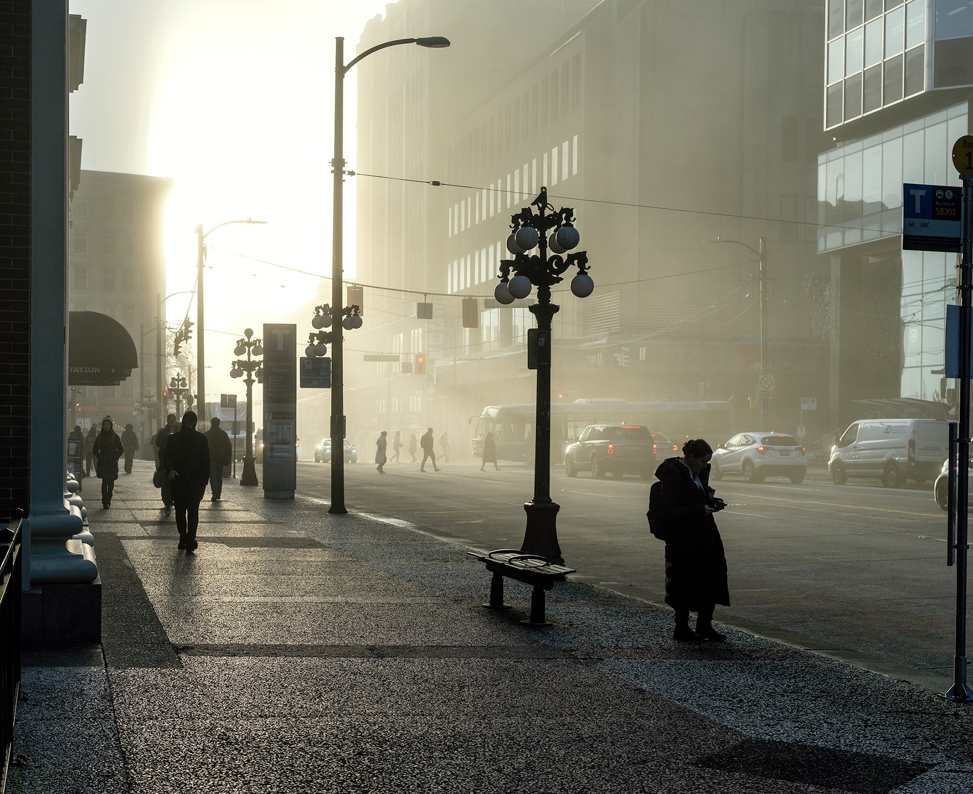 Lone woman at a busstop on a foggy morning, people going to work.