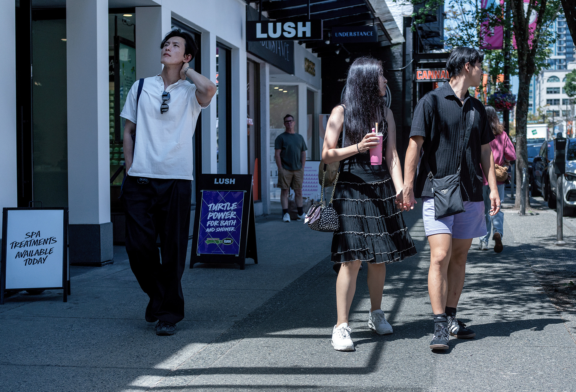 Curious street scene, one man posing as others look away, man in the background watches.
