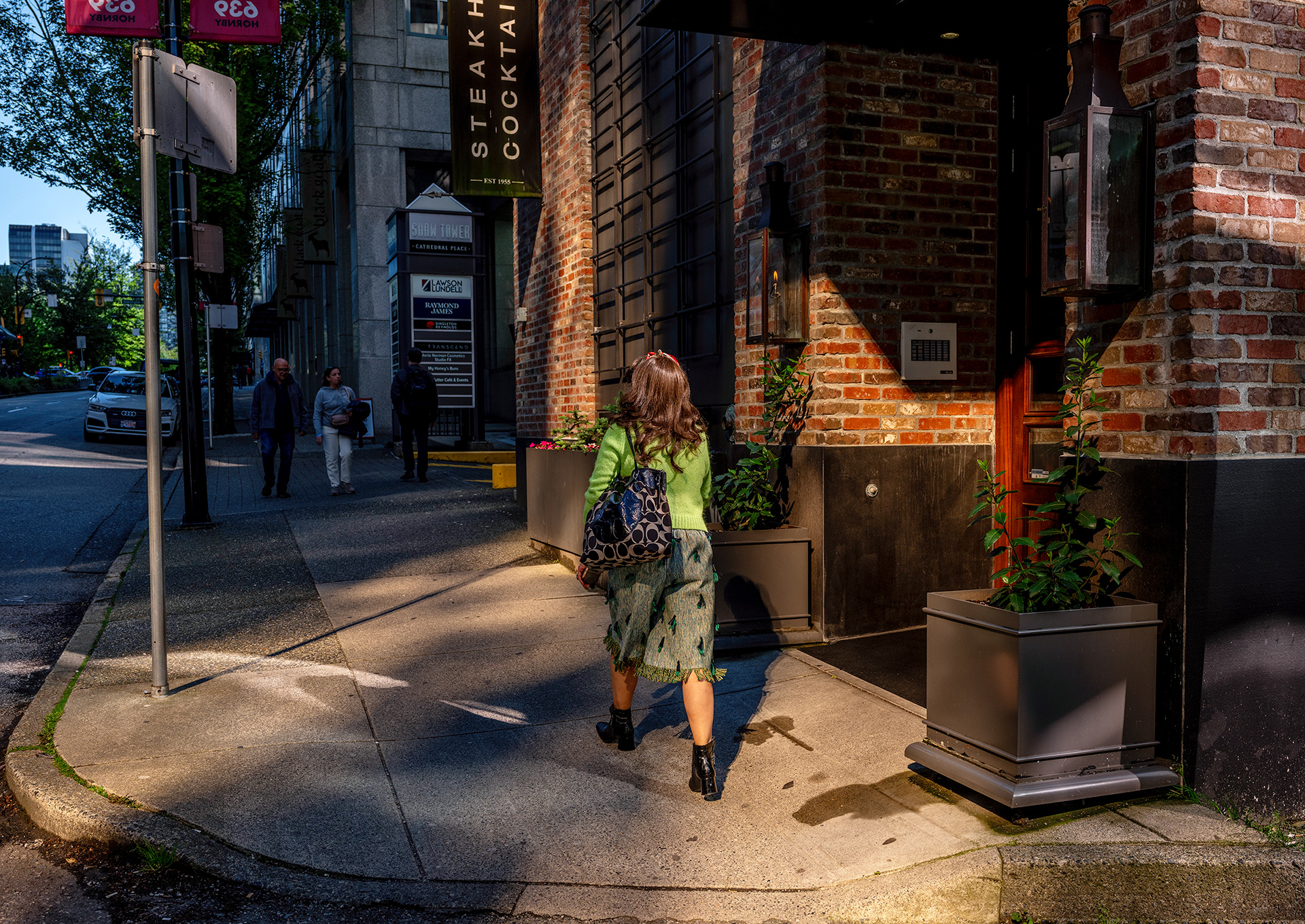 Mixed lighting on a woman in a green outfit, outside a bar.