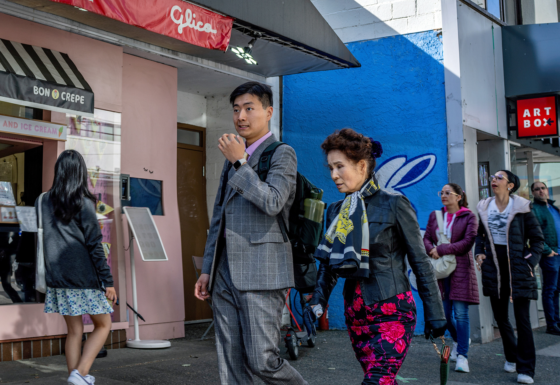 Couple strolling man gesturing, woman with fairy wings, daytime, colourful.