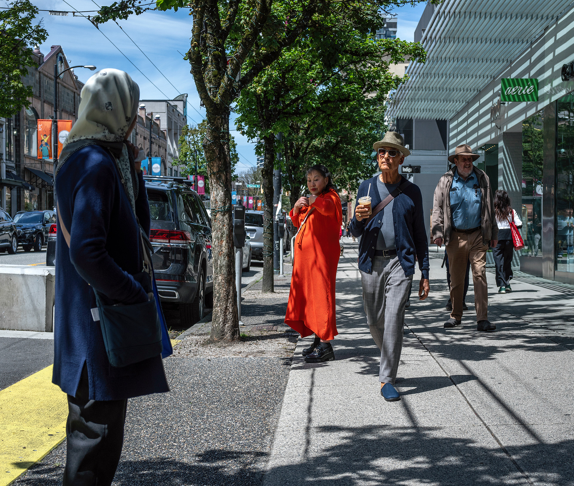 Sunny day on Robson Street in Vancouver, people strolling trees sky and a colourful mix of people.